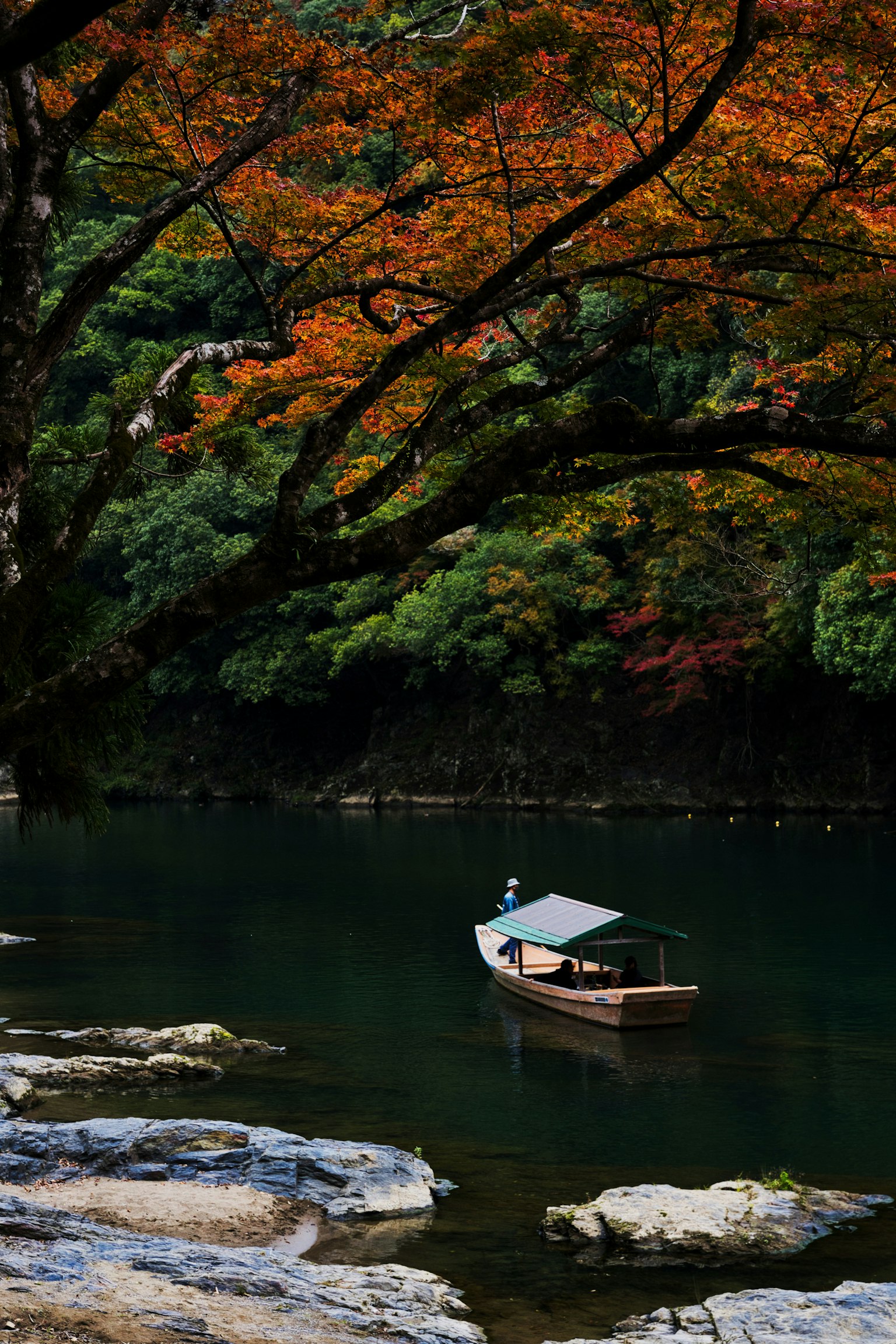秋の紅葉に囲まれた静かな川で小舟が浮かぶ風景