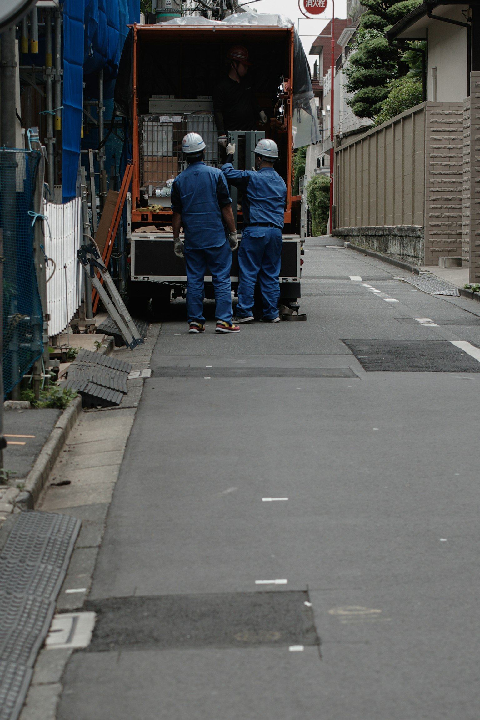 Two workers in blue uniforms and helmets working in a truck's cargo area