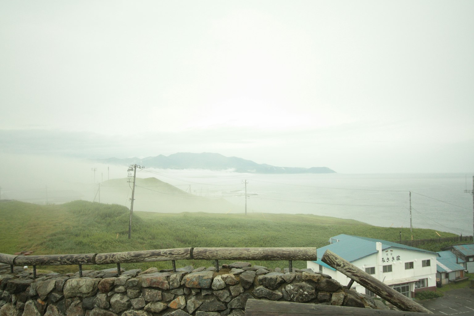 Paisaje costero brumoso con colinas verdes e islas distantes
