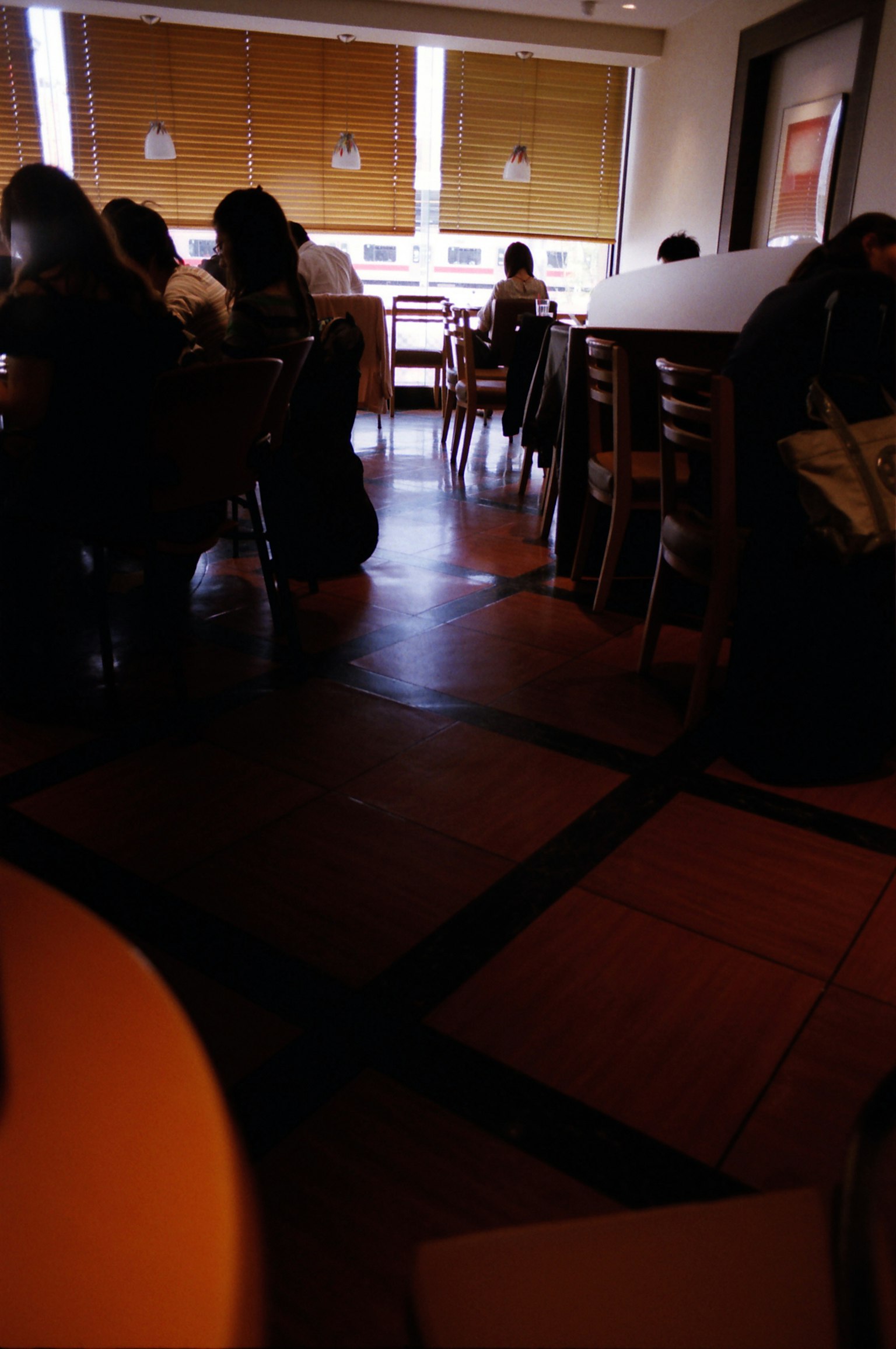 Intérieur de café tranquille avec des tables et chaises en bois éclairées par la lumière naturelle des fenêtres