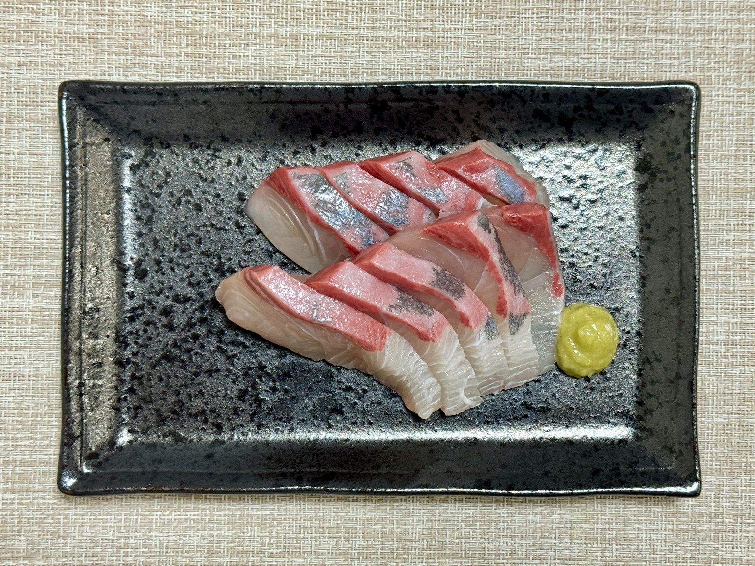 Sashimi thái lát trên đĩa đen với wasabi