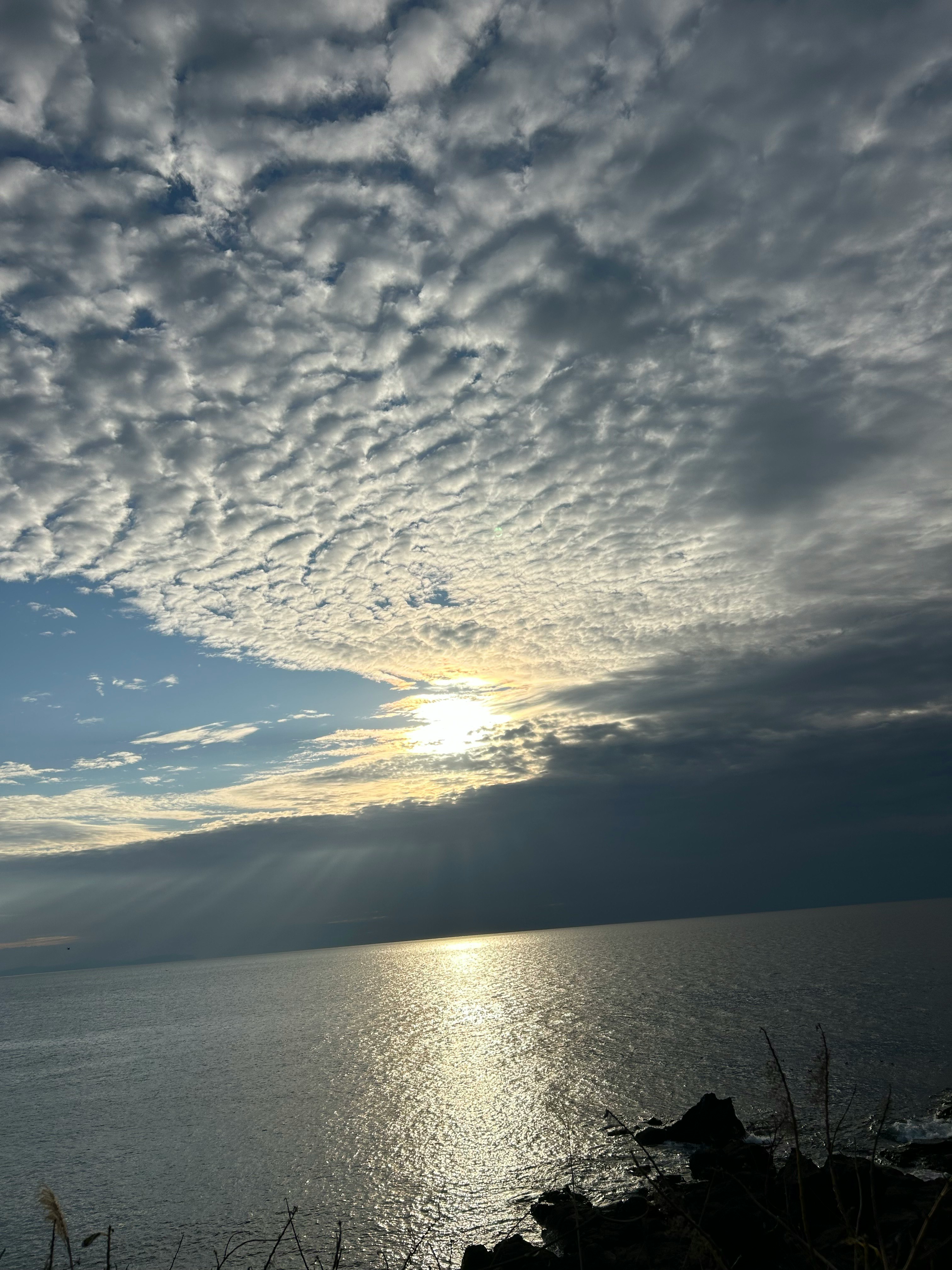 夕日に照らされる海面と雲の広がる風景