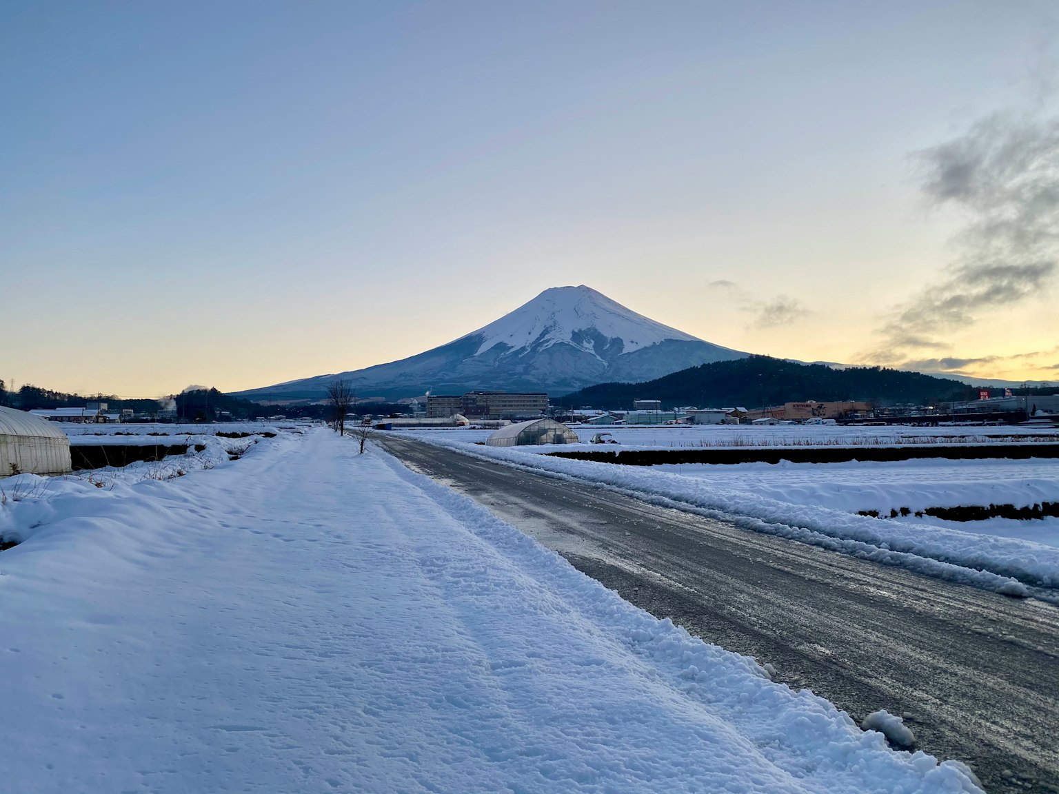Snow-covered view of Mount Fuji with a quiet road