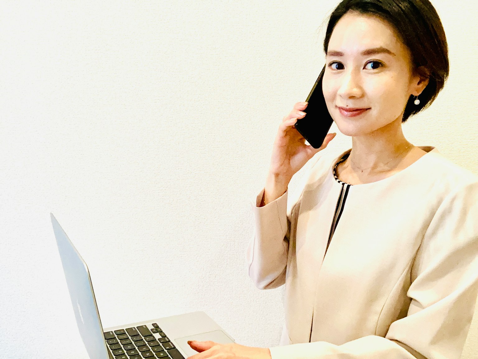 Seorang wanita memegang telepon sambil berdiri di depan laptop