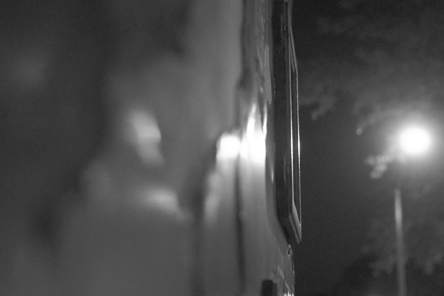 夜の街灯と壁の一部が映るモノクロ写真