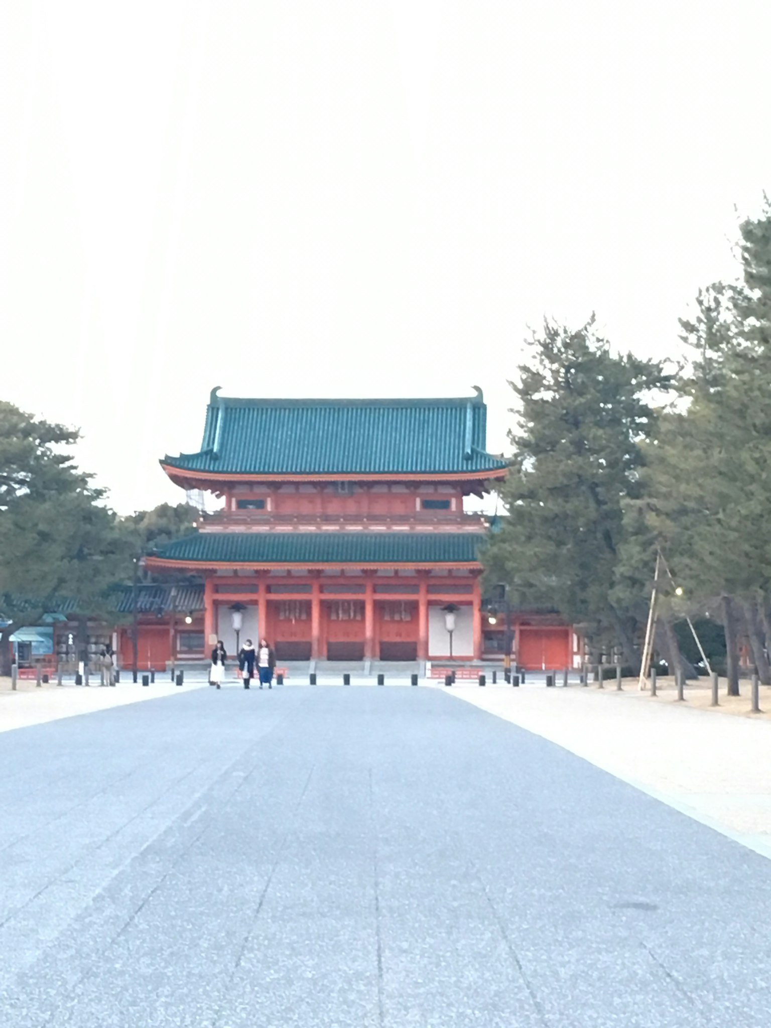 Bâtiment traditionnel japonais avec une porte rouge et un toit vert au premier plan