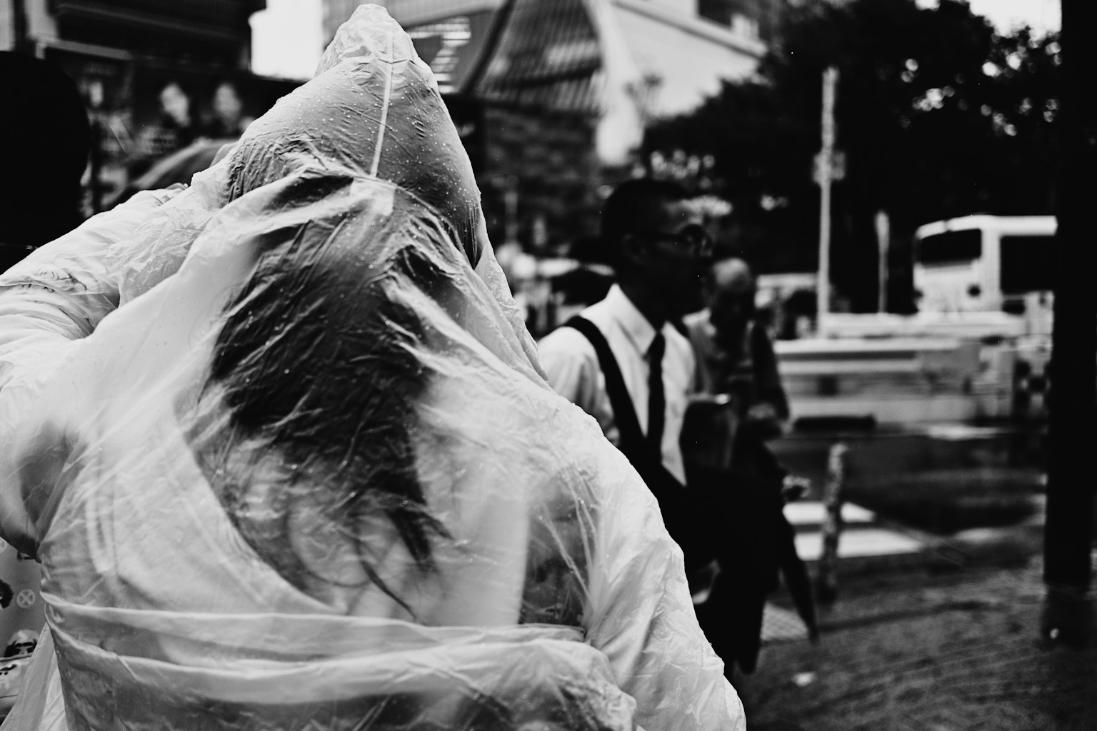 Scena di strada in bianco e nero con persone in abbigliamento impermeabile