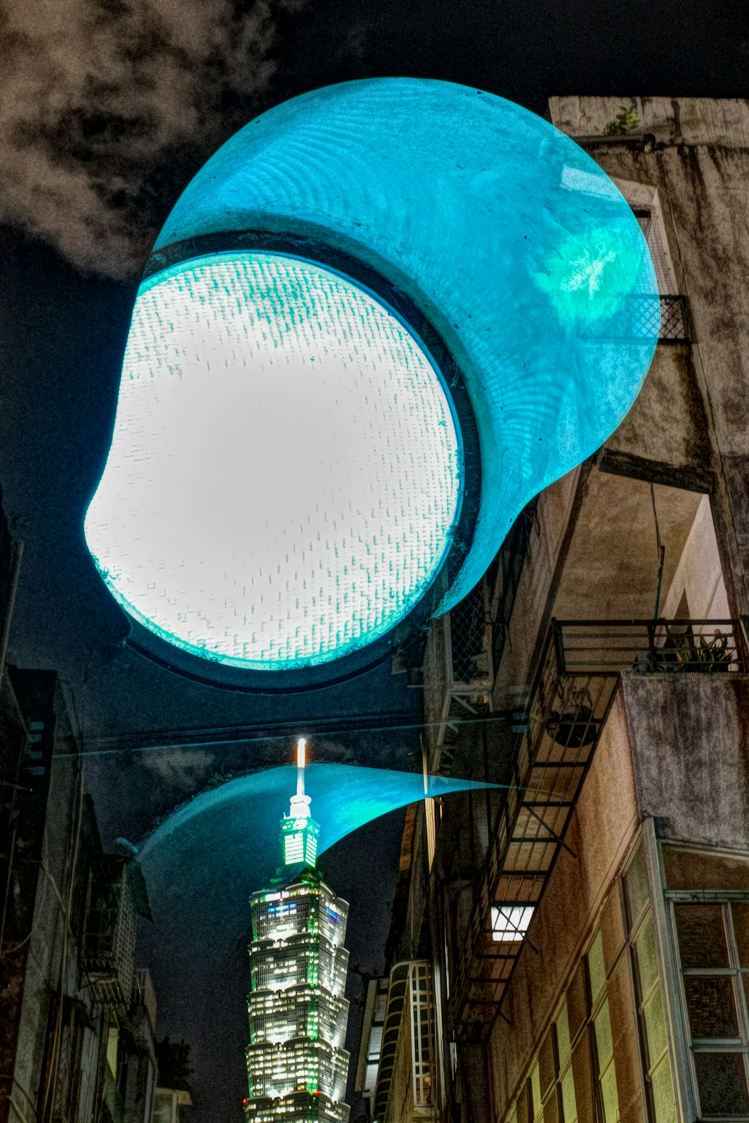 Large blue illuminated object with Taipei 101 in the background at night