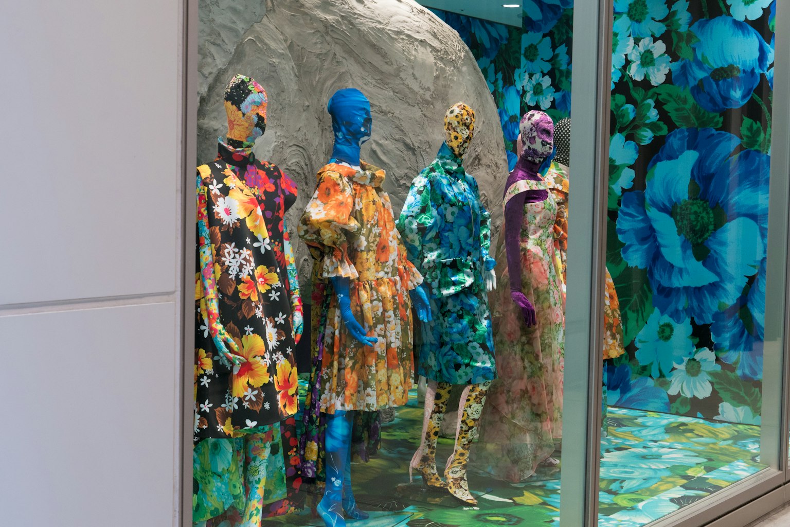 Colorful mannequins in floral dresses displayed in a shop window