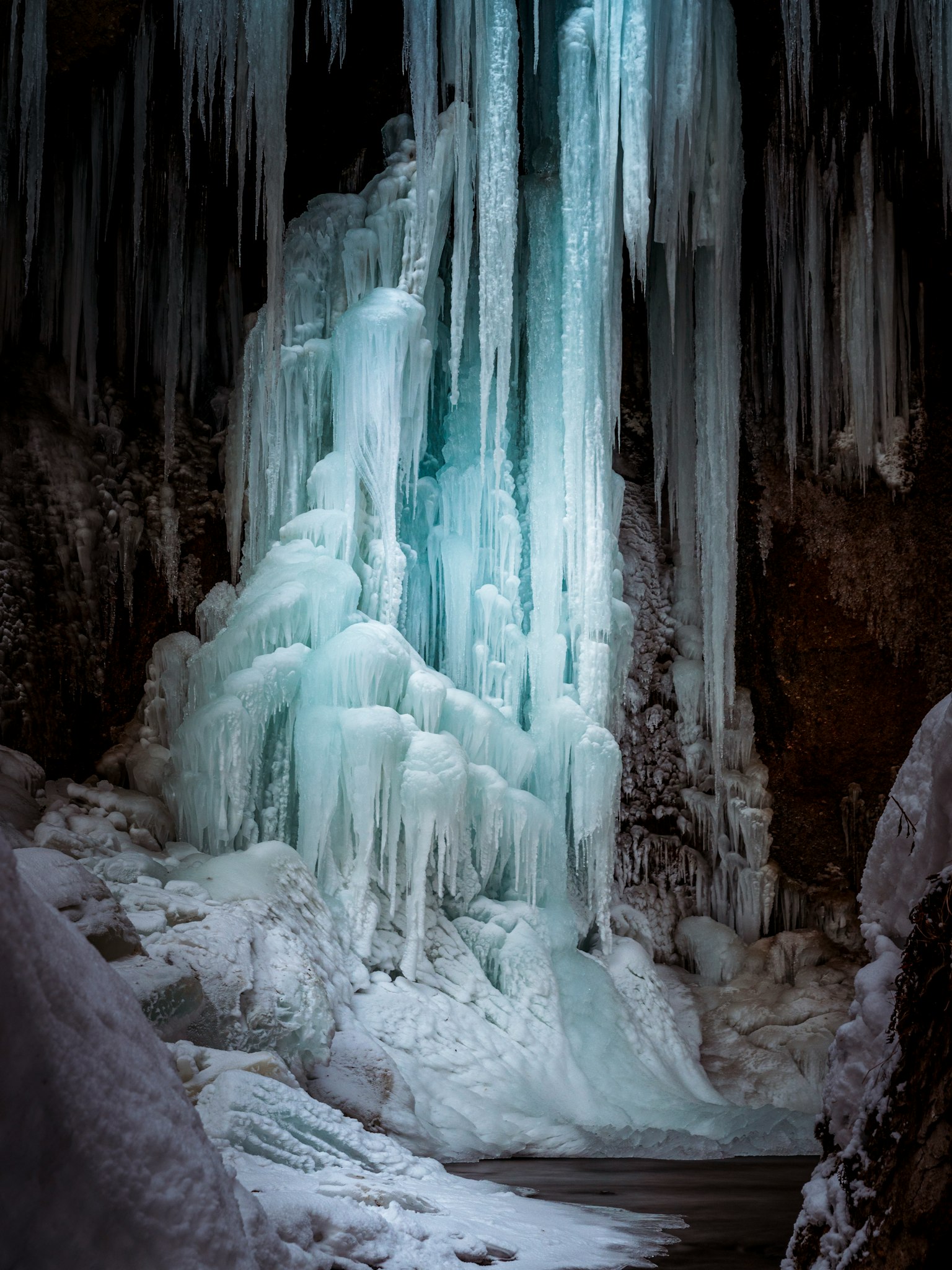 Icy waterfall with pale blue light inside a cave