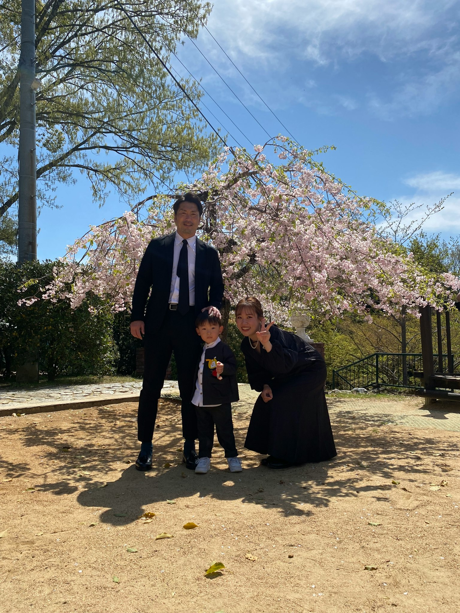 Foto familiar bajo un cerezo con padres e hijo sonriendo
