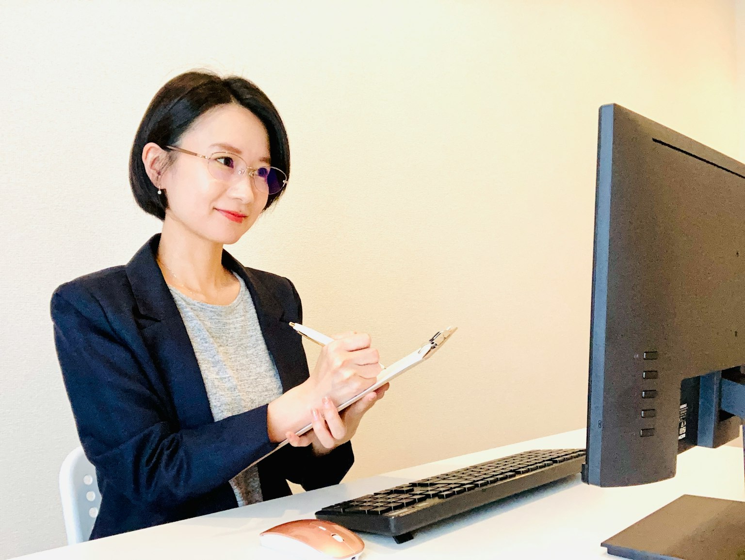 Donna d'affari che prende appunti a una scrivania con un computer