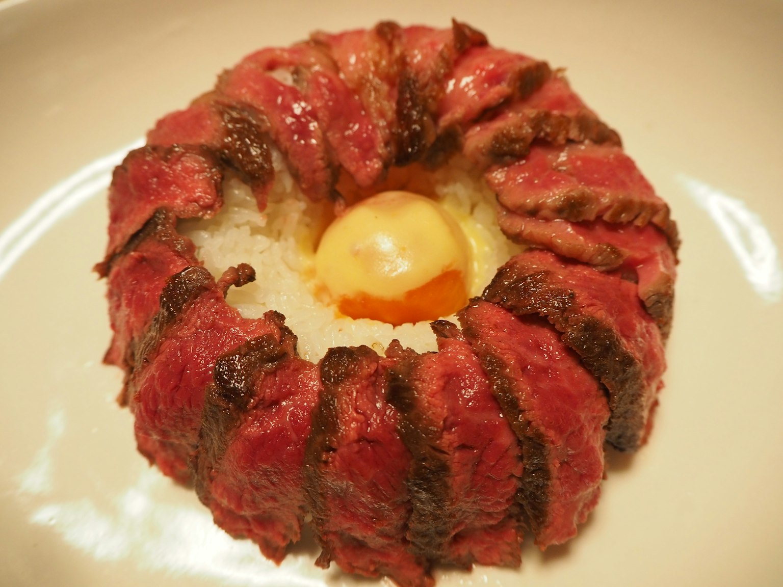 一圈烤肉围绕着米饭和一个鸡蛋