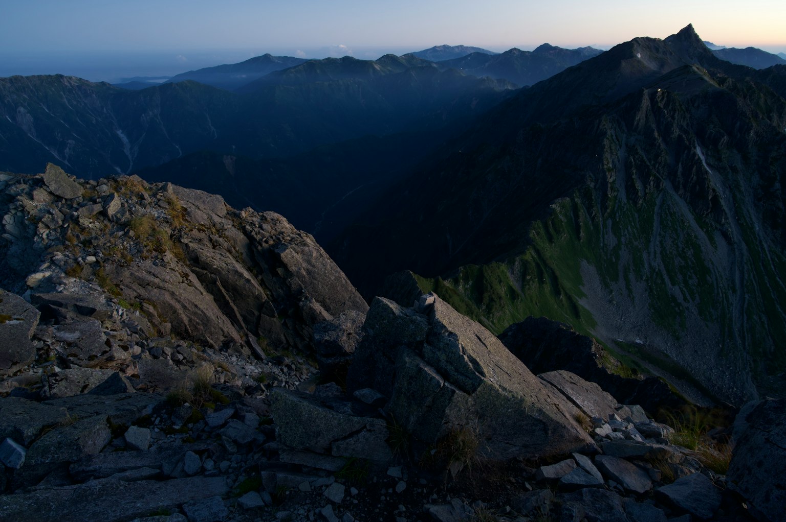 Immagine di una cima montuosa scura con una vista mozzafiato sulle montagne circostanti