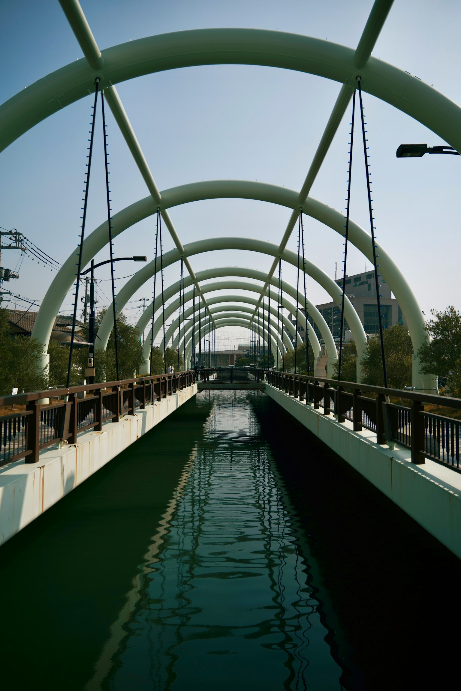 Jembatan lengkung di atas saluran air hijau dengan desain modern