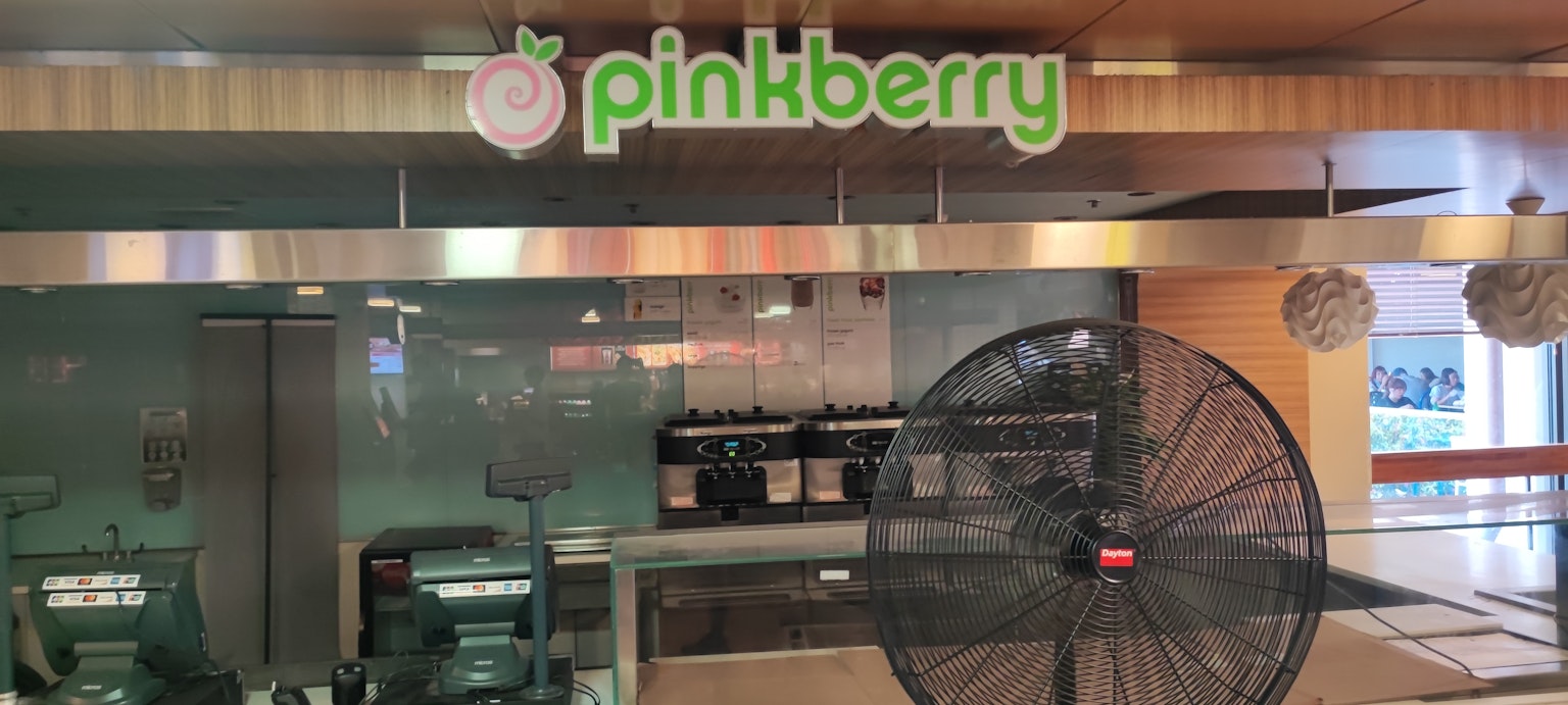 Vista interior de una tienda Pinkberry con mostrador de acero inoxidable y equipo
