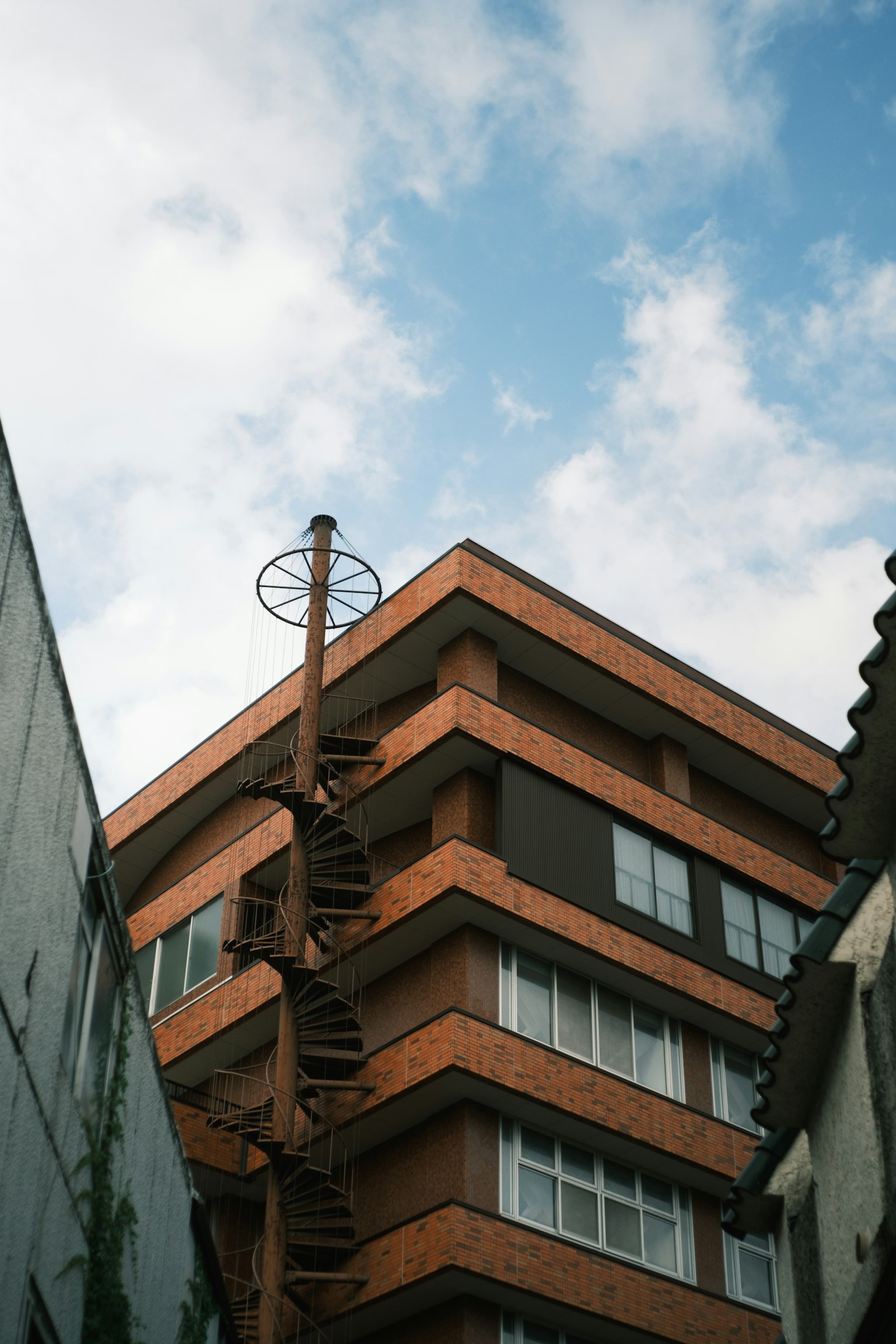 Tòa nhà gạch đỏ với cầu thang xoắn ốc dưới bầu trời nhiều mây