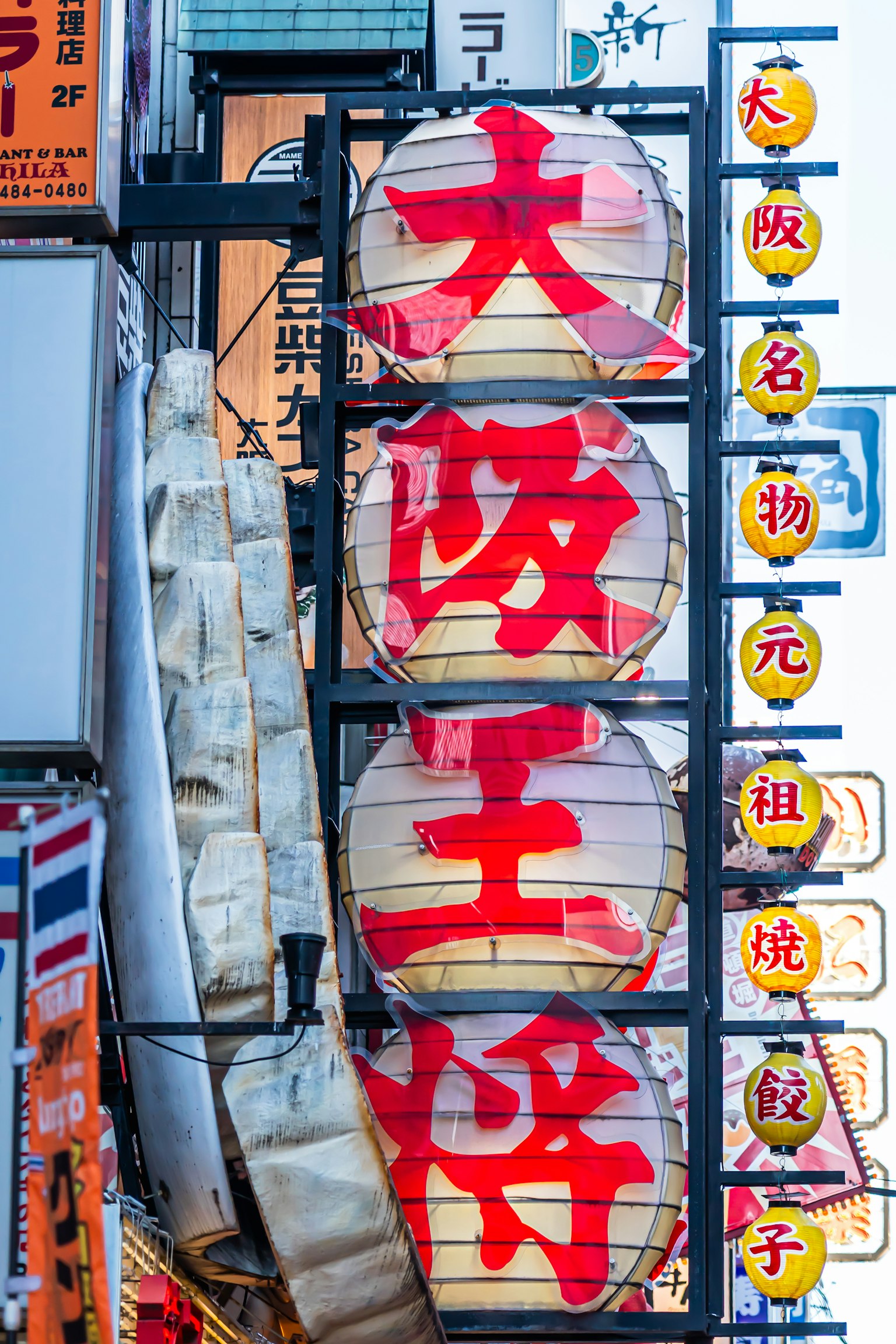 Lanterne illuminate con caratteri rossi audaci nella vivace scena di strada di Osaka