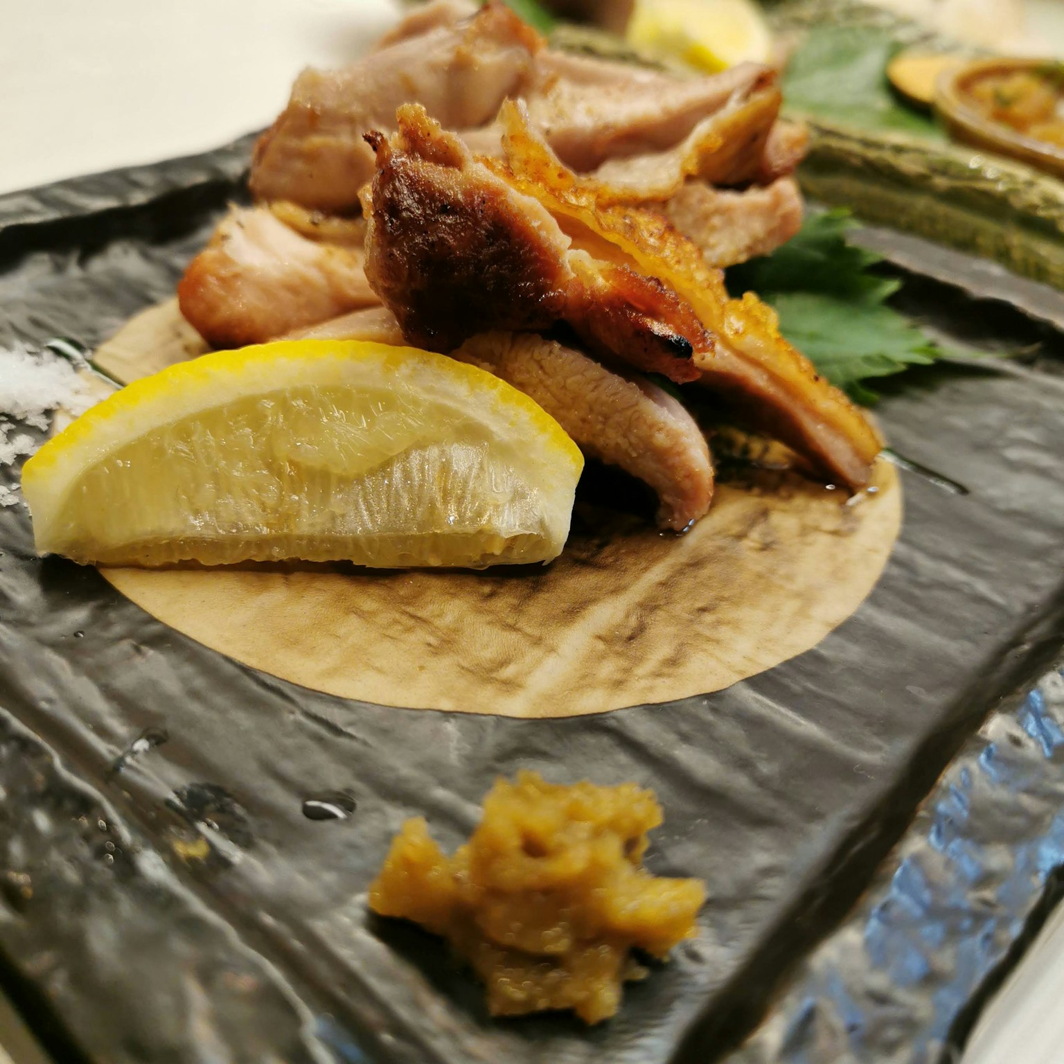 A beautifully arranged plate featuring grilled chicken and lemon slices