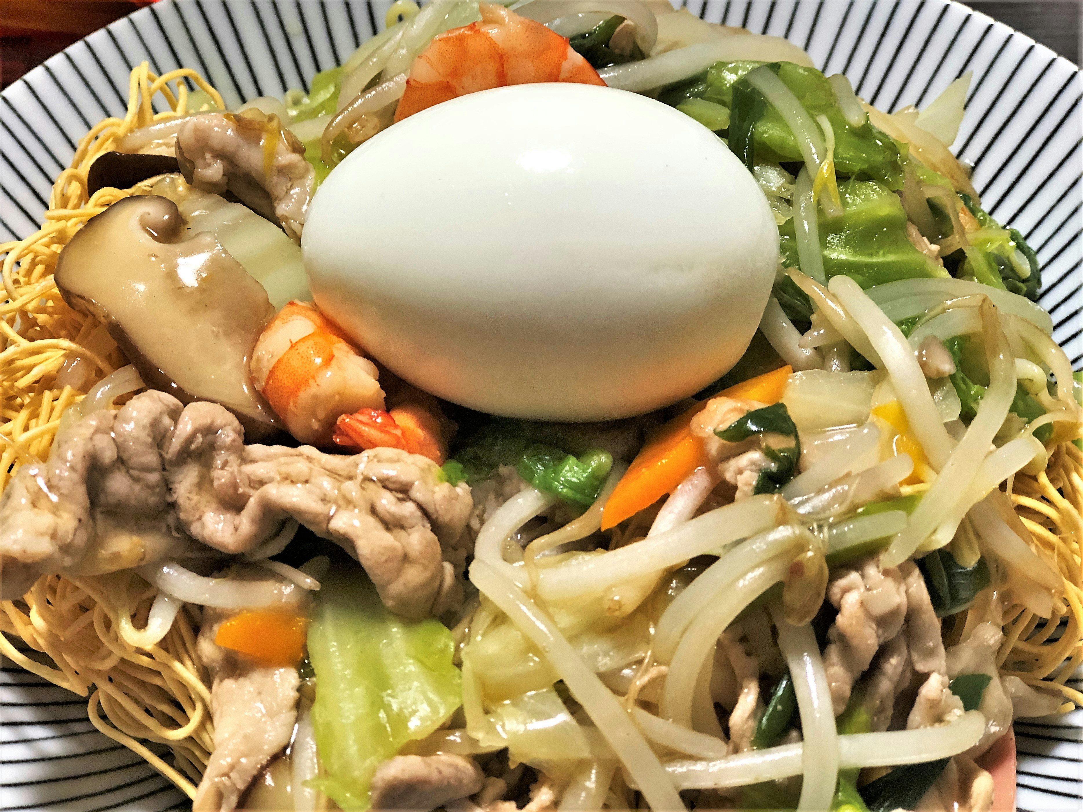 皿に盛られた焼きそば風麺と野菜、温泉卵