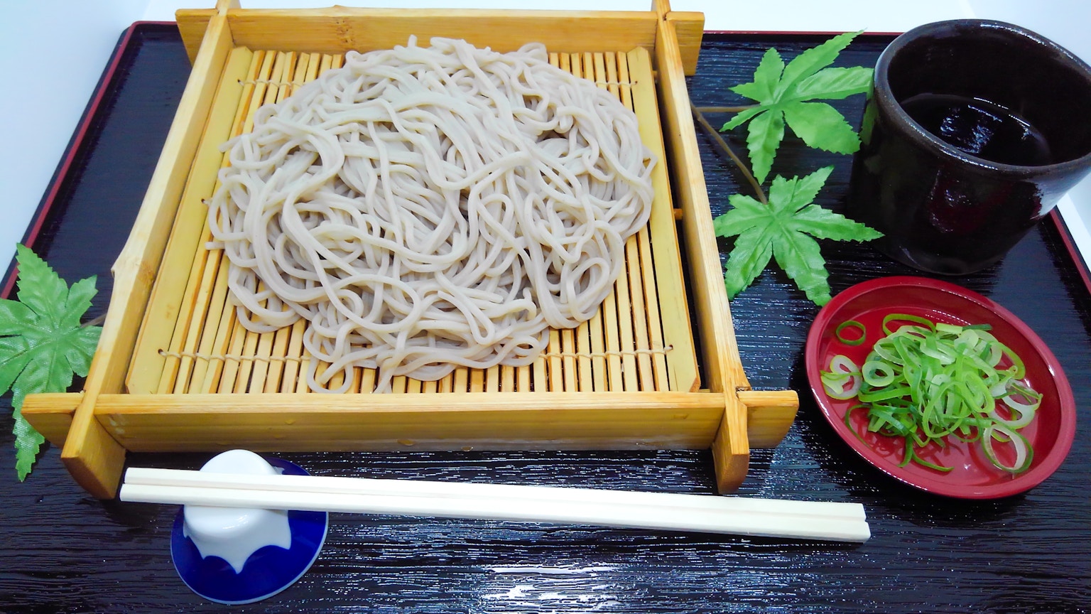 Zaru soba served on a bamboo tray with dipping sauce and green onions