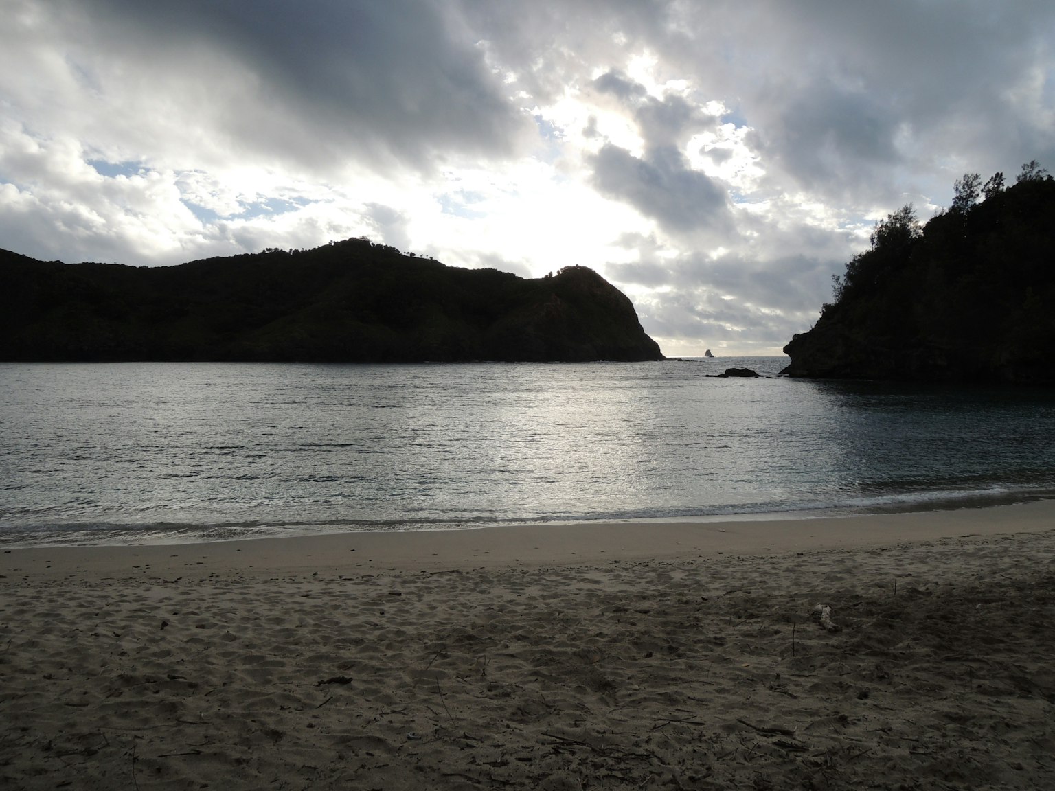 Serene beach scene with calm sea and dark clouds in the distance