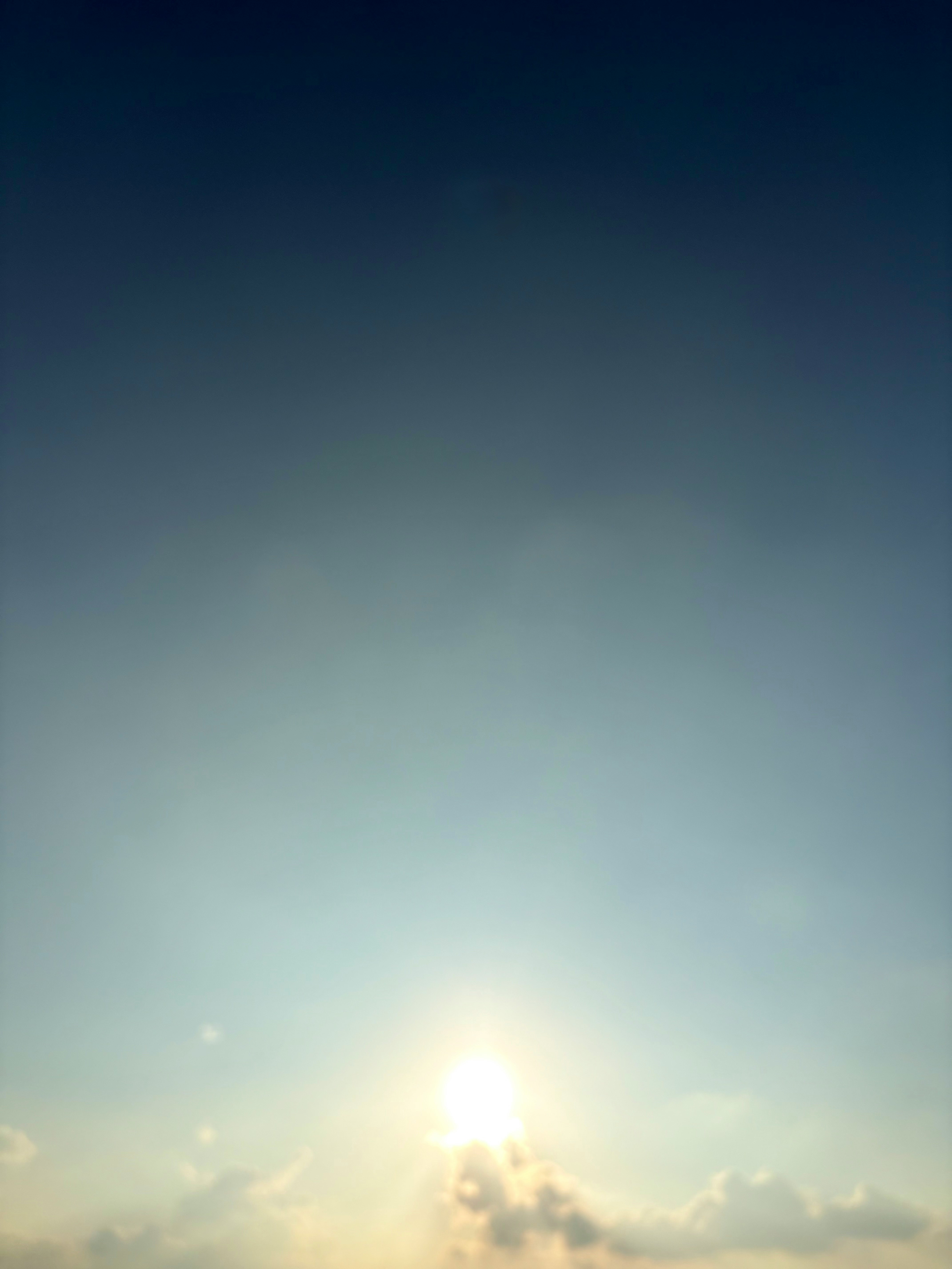 青空の下で雲の間から差す太陽の光