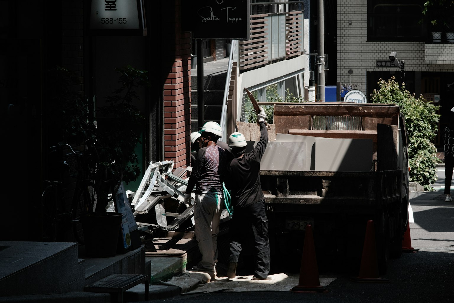 Due lavoratori in uniforme che caricano rifiuti su un camion in un ambiente urbano