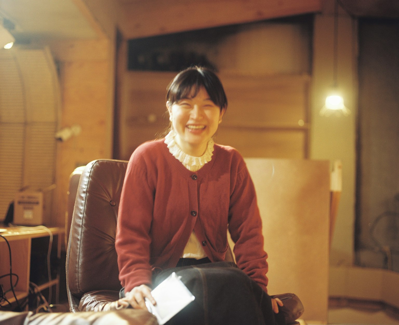 Femme souriante portant un cardigan rouge dans un cadre intérieur