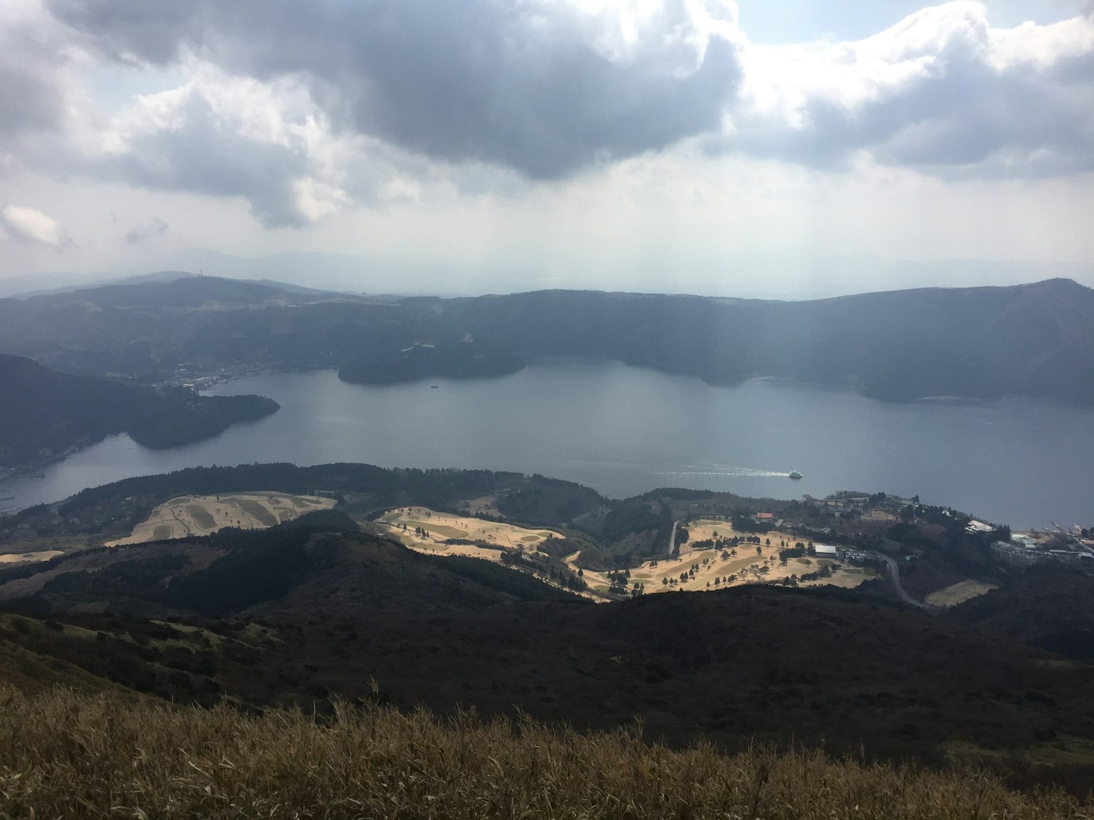 Panoramablick auf einen See umgeben von Hügeln und Wolken