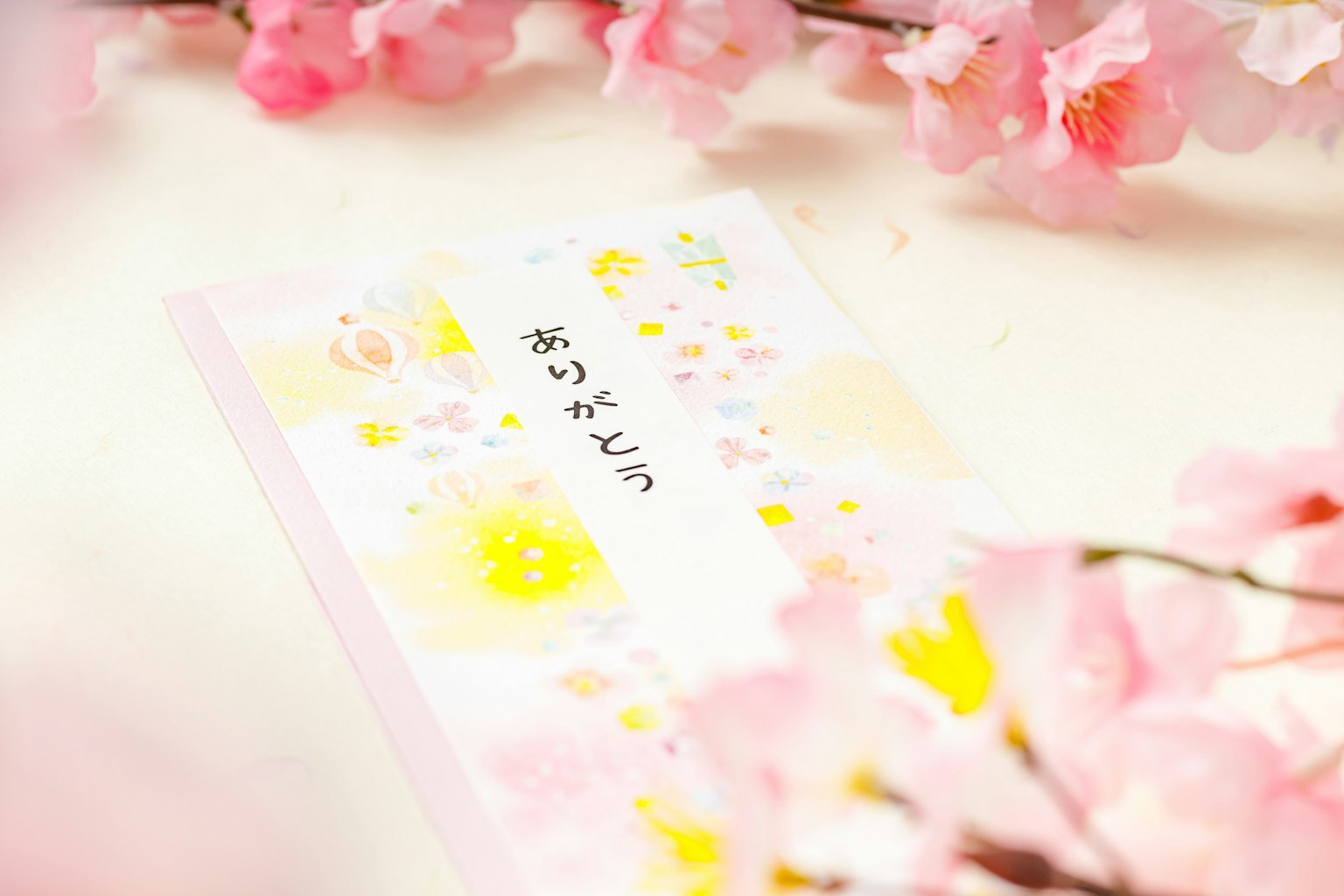 Kartu pesan Jepang dikelilingi oleh bunga sakura