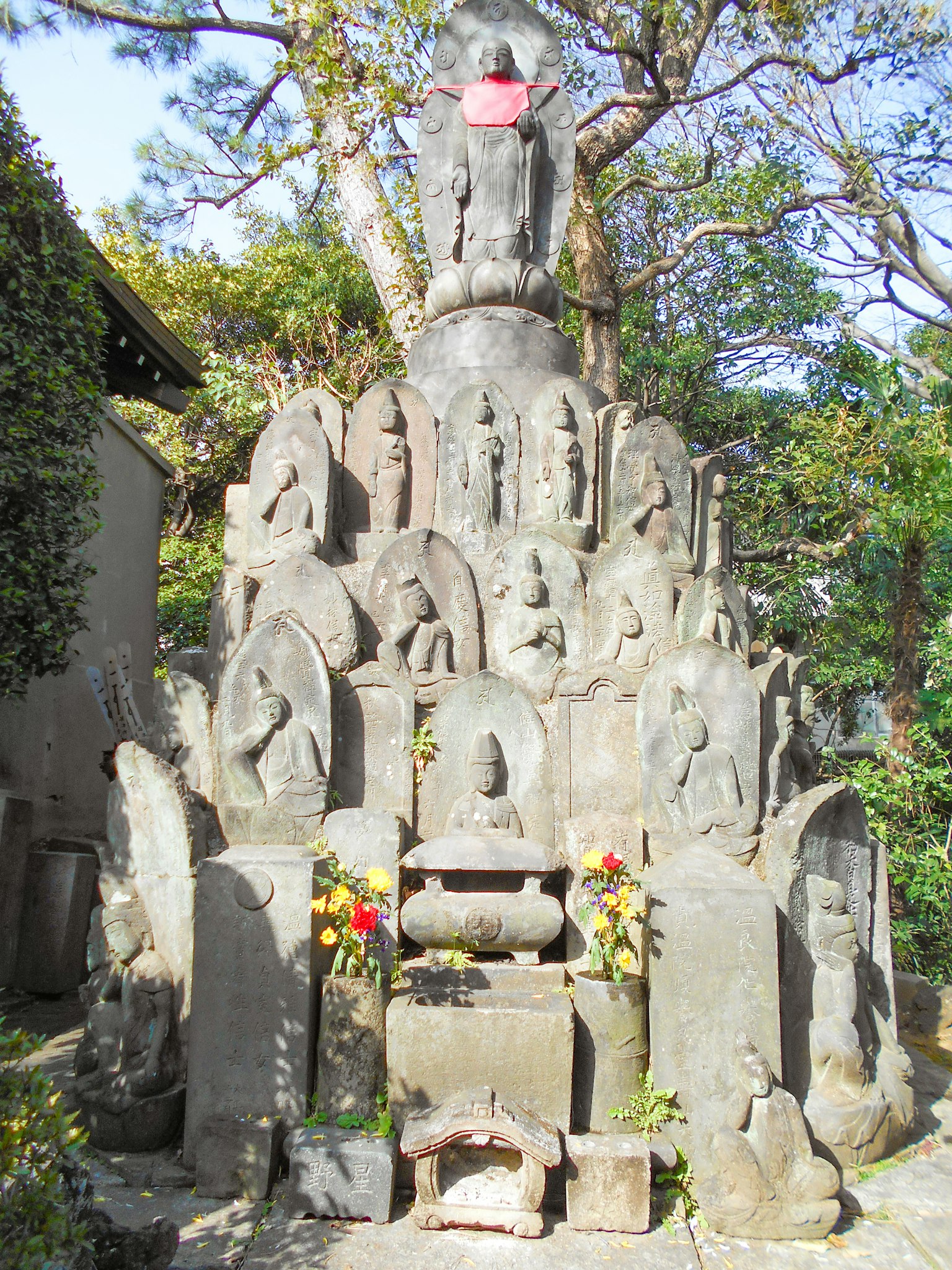 Stone tower with multiple Buddha statues and an altar decorated with flowers