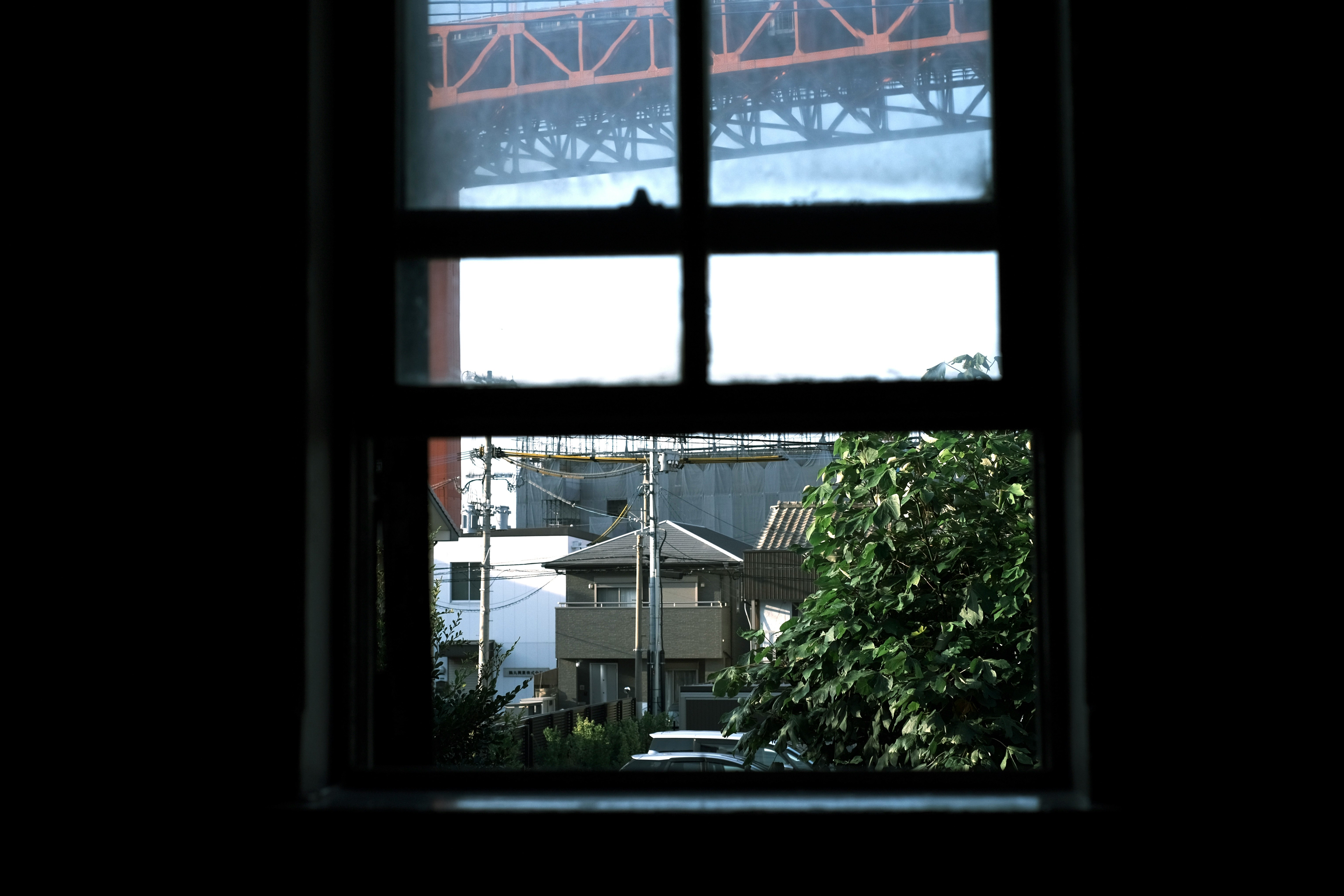 View of a railway bridge and cityscape through a window frame
