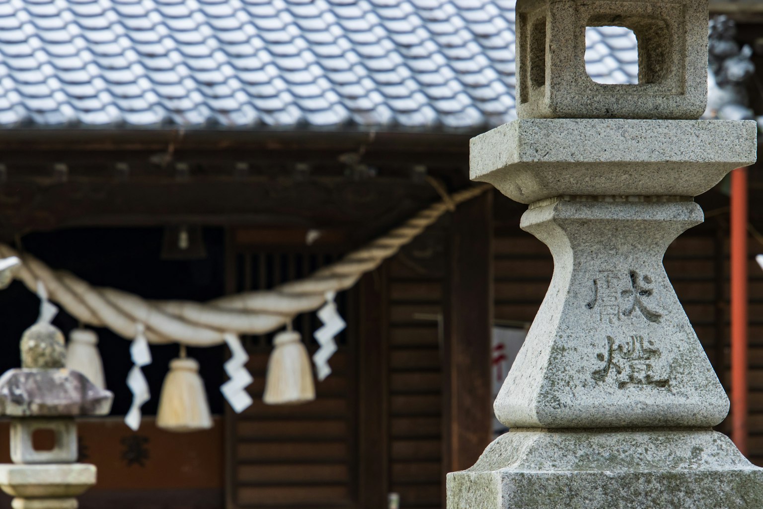 Traditional Japanese landscape featuring a stone lantern and shrine backdrop
