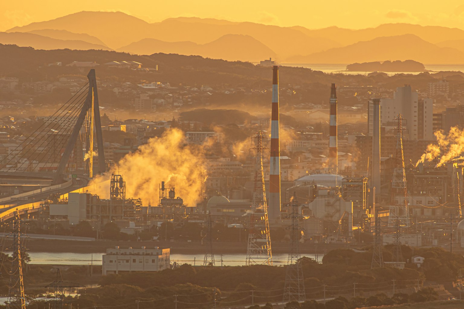 Area industriale con fabbriche e ciminiere al tramonto