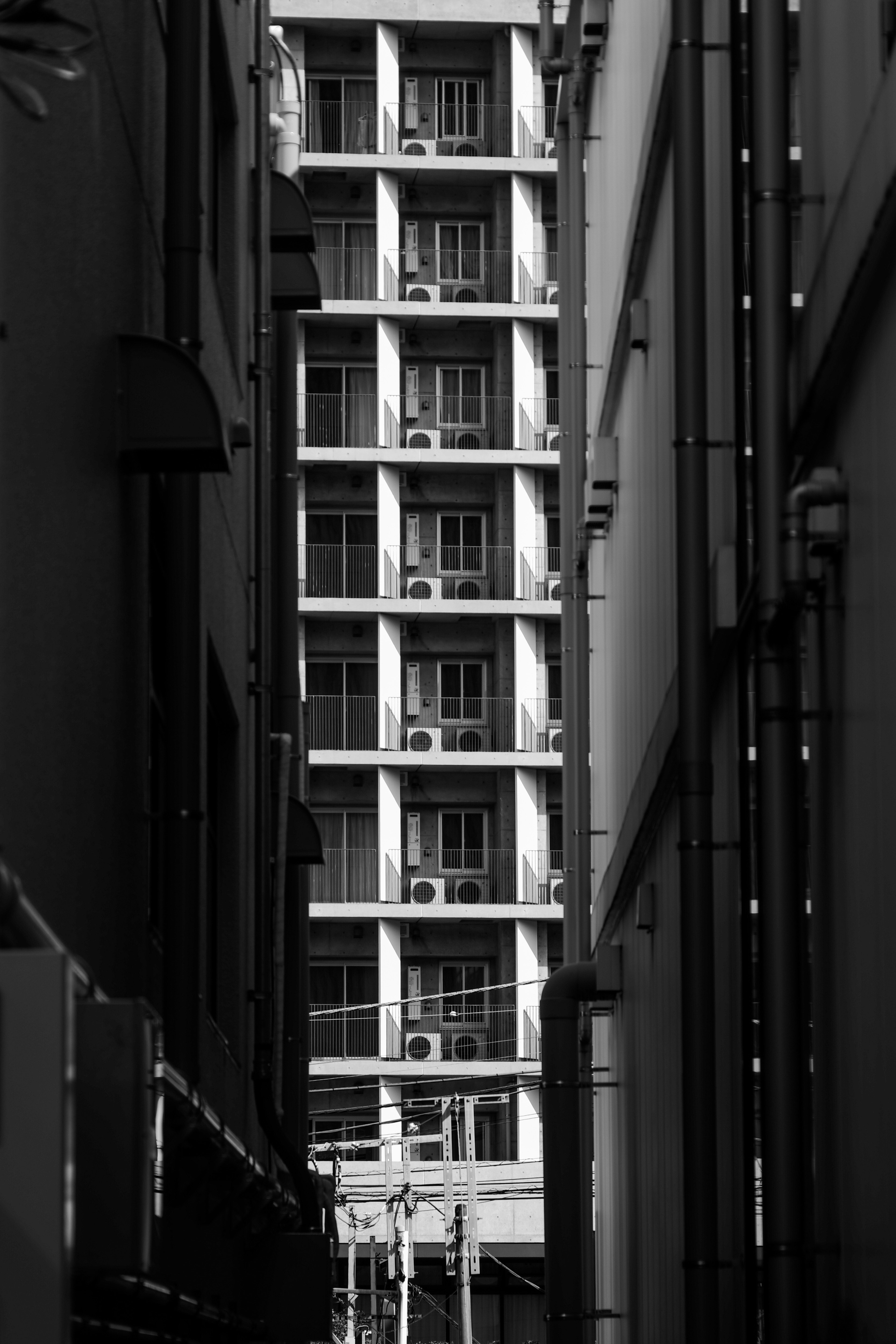 Narrow urban alley with a grid-like building facade in the distance