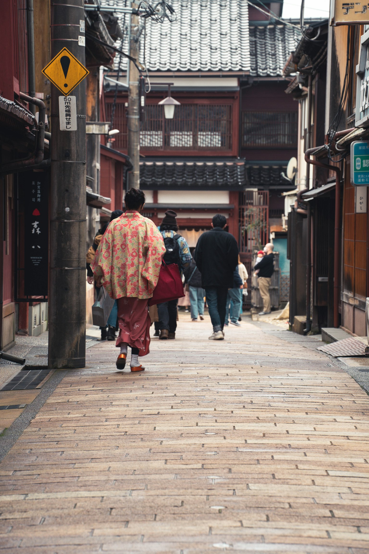 Una mujer en kimono caminando por una calle tradicional con gente