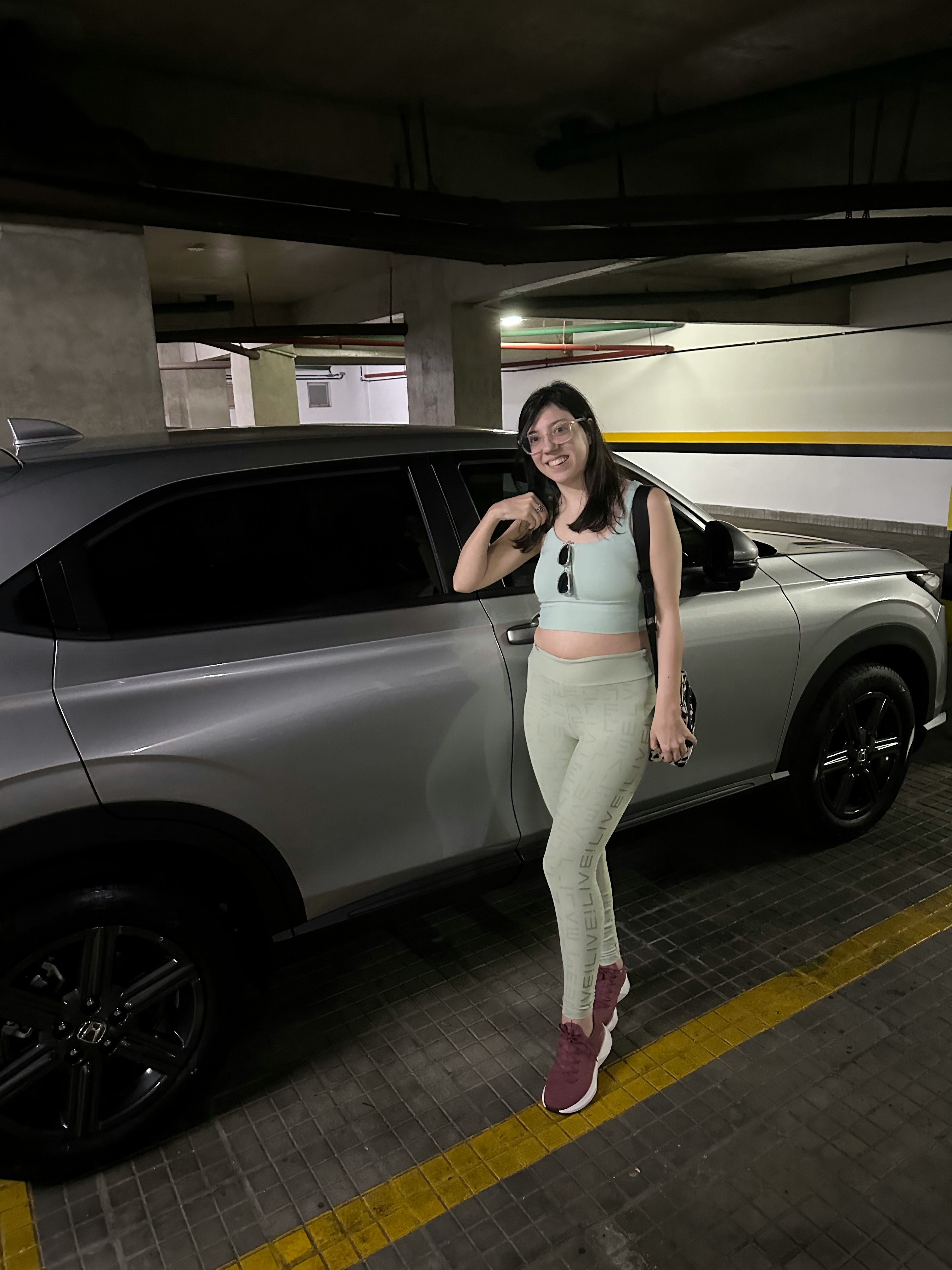 室內停車場裡站在汽車旁的女性