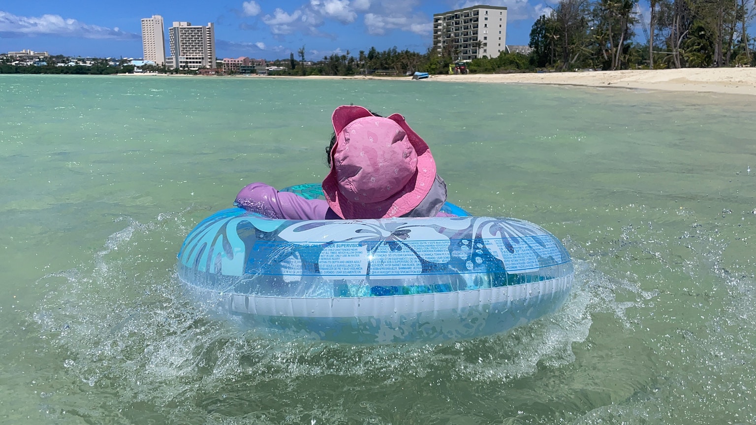 Un oso de peluche rosa flotando en un anillo inflable azul en el agua