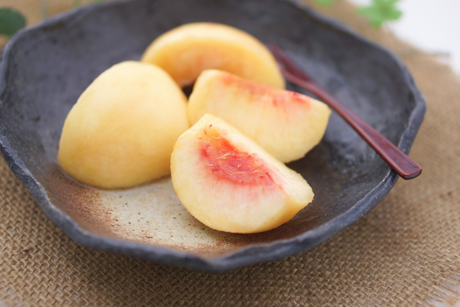 Pesche affettate su un piatto scuro con un cucchiaio