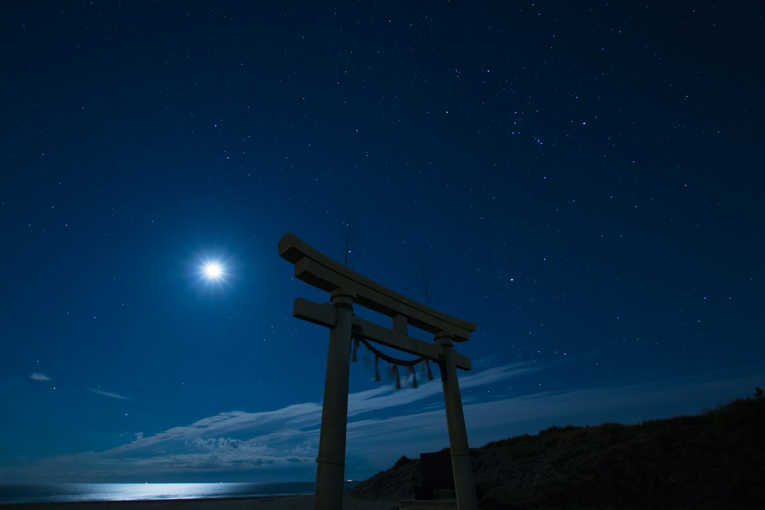 Pemandangan indah sebuah torii di bawah langit malam biru dengan bulan purnama