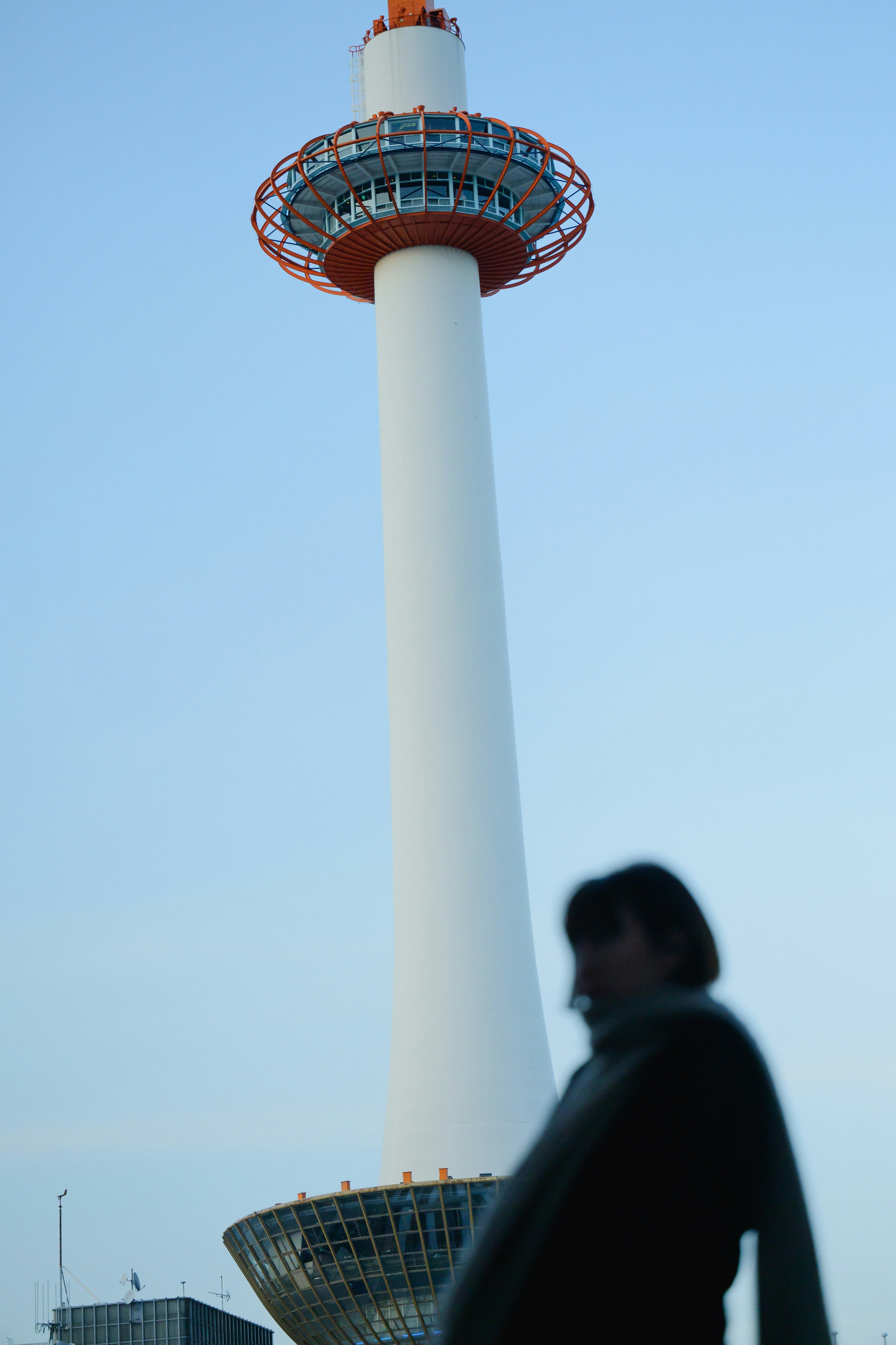 青空の下にそびえる展望塔と人物のシルエット