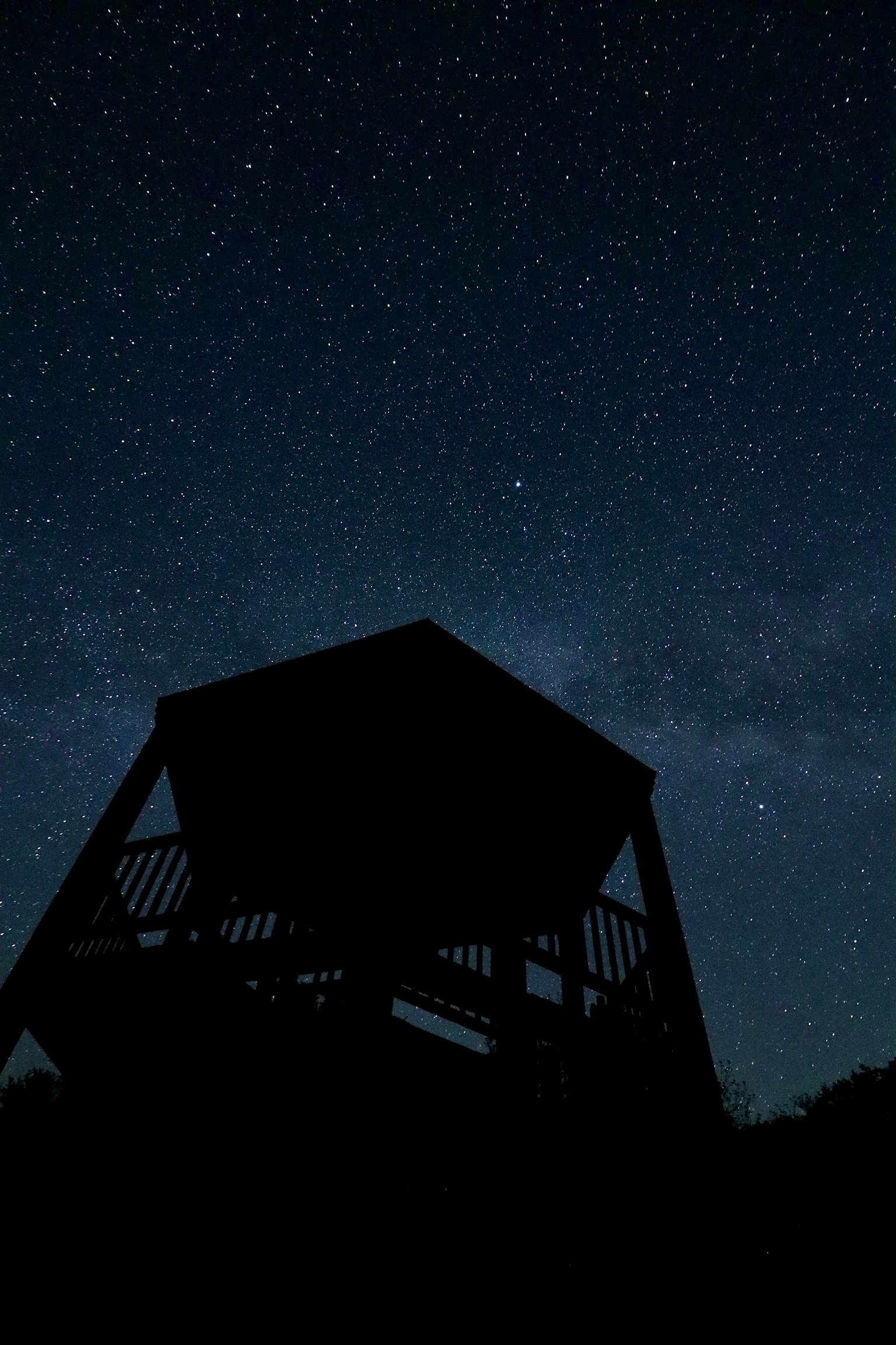 Cabaña de observación en silueta bajo un cielo estrellado