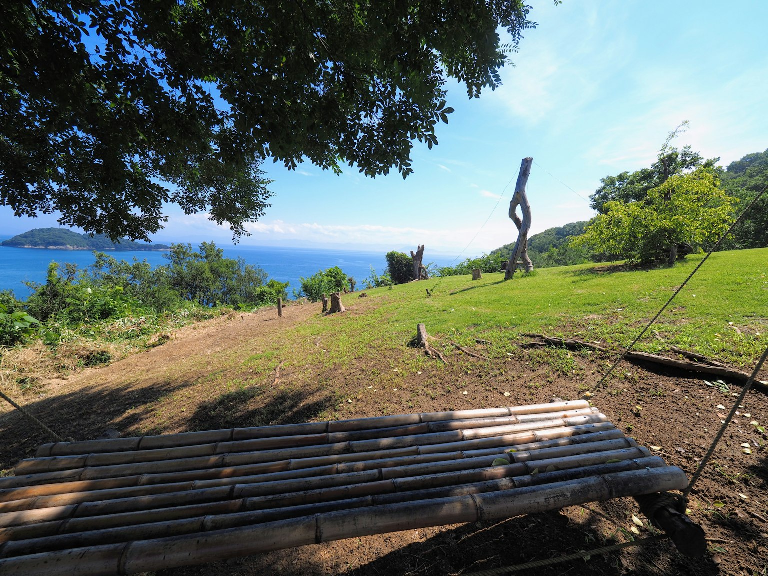 Panchina in bambù con vista su un paesaggio verde e scultura