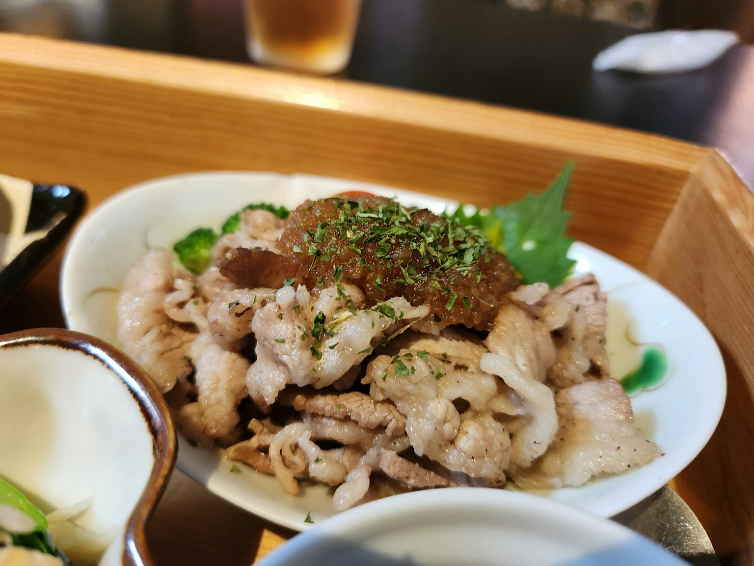 切片豬肉料理，白色盤子上裝飾著香草