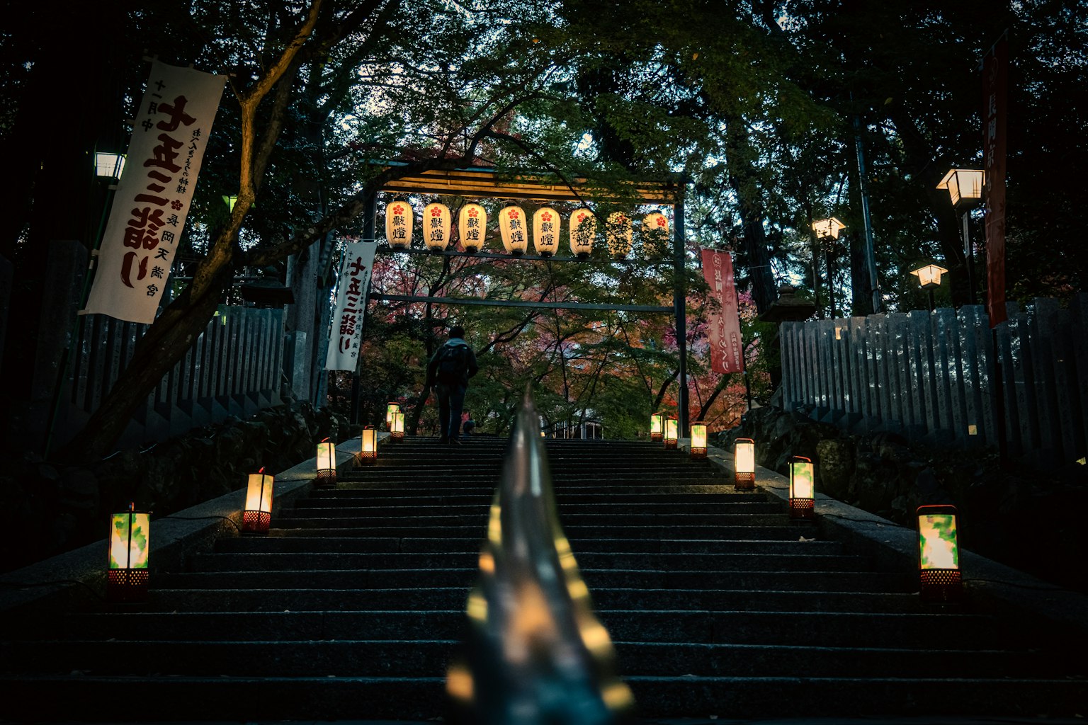 บันไดที่มีโคมไฟอยู่สองข้างนำไปสู่ตึกใต้ท้องฟ้ายามค่ำคืน
