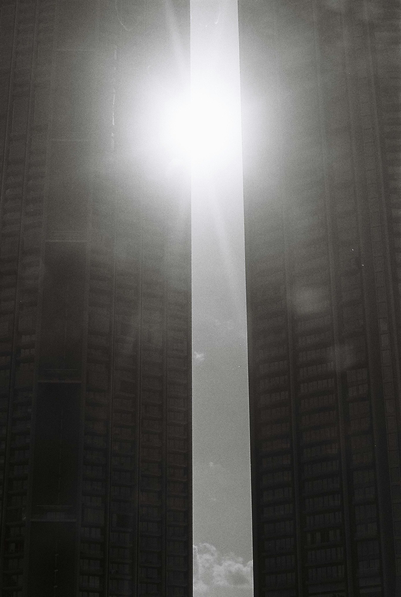 高層ビルの間から差し込む光と雲