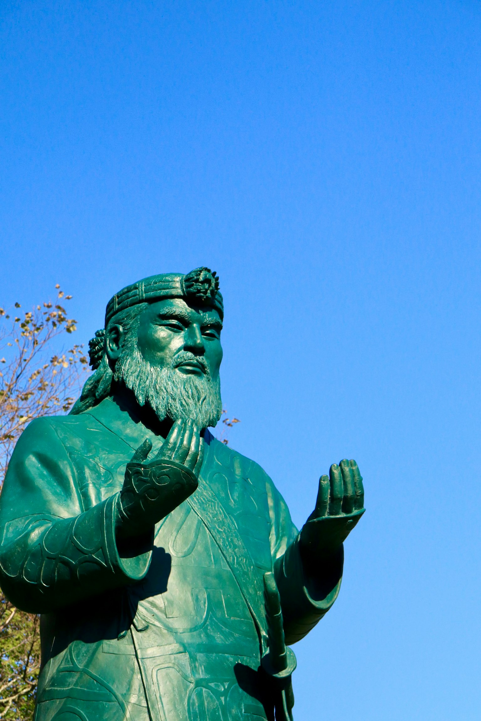 Estatua de bronce con las manos extendidas contra un cielo azul claro