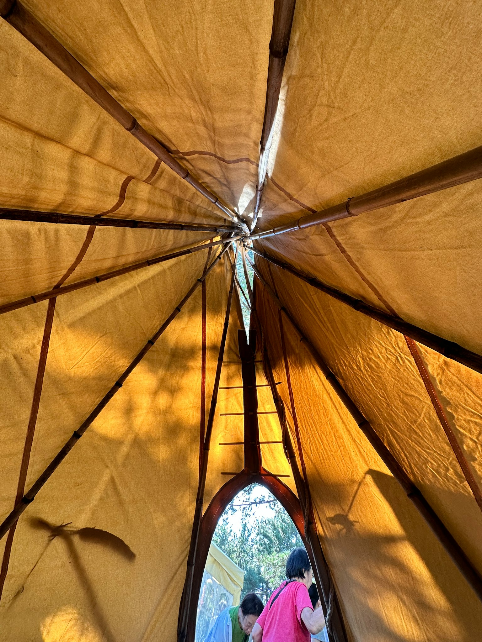 Pemandangan dari dalam tenda melihat ke atas dengan kain kuning dan struktur kayu