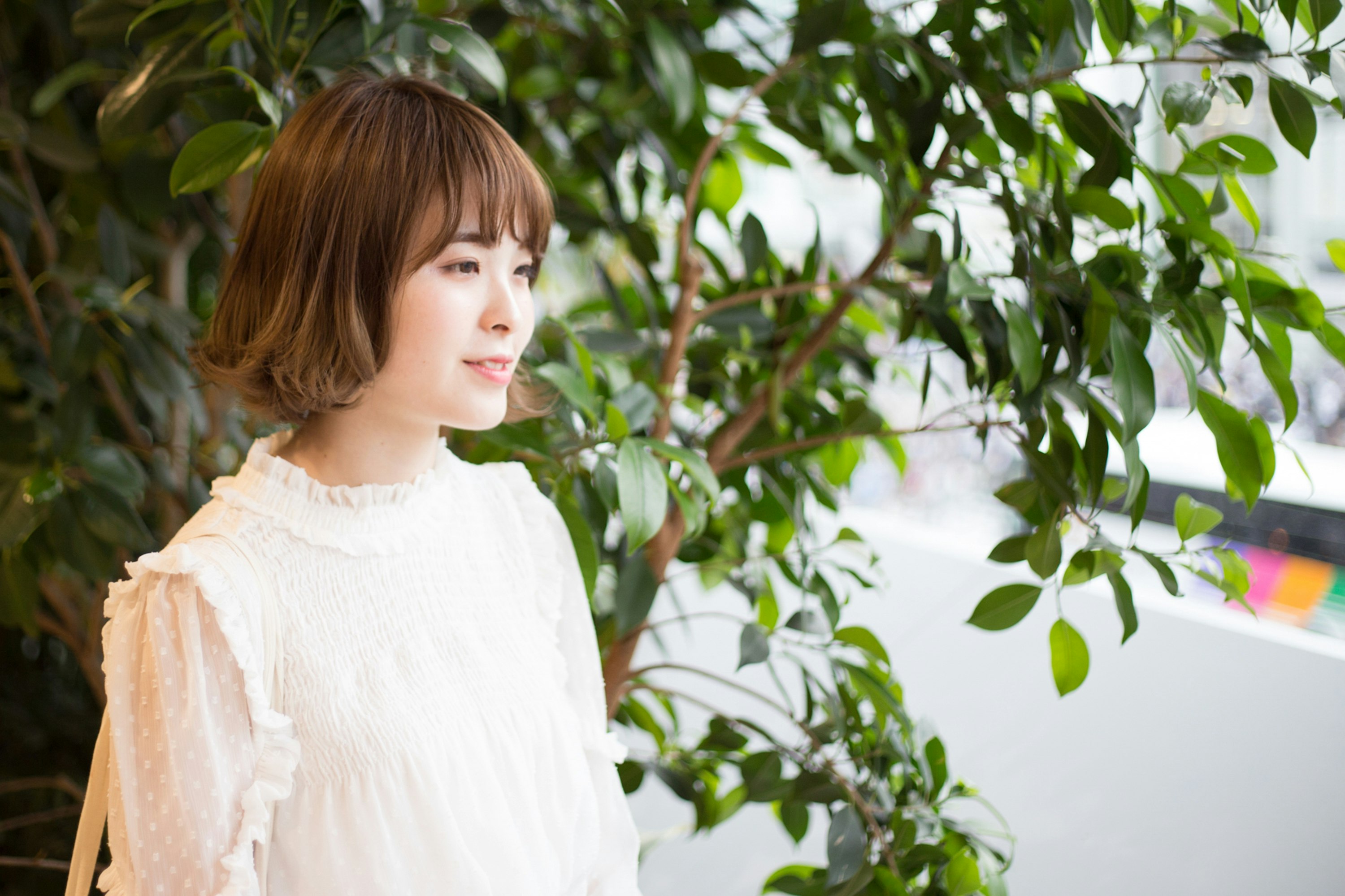 観葉植物に囲まれた屋外の女性